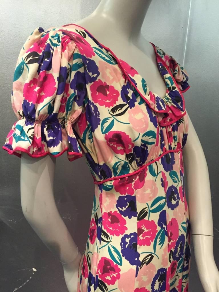 A gorgeous 1930s silk floral bias-cut gown in an abstract floral pattern of pink, fuchsia, purple, teal and black. Gathered front bust and ruffled puff sleeves and neckline. fuchsia piping trim and back tie. Side hook and eye closure. 