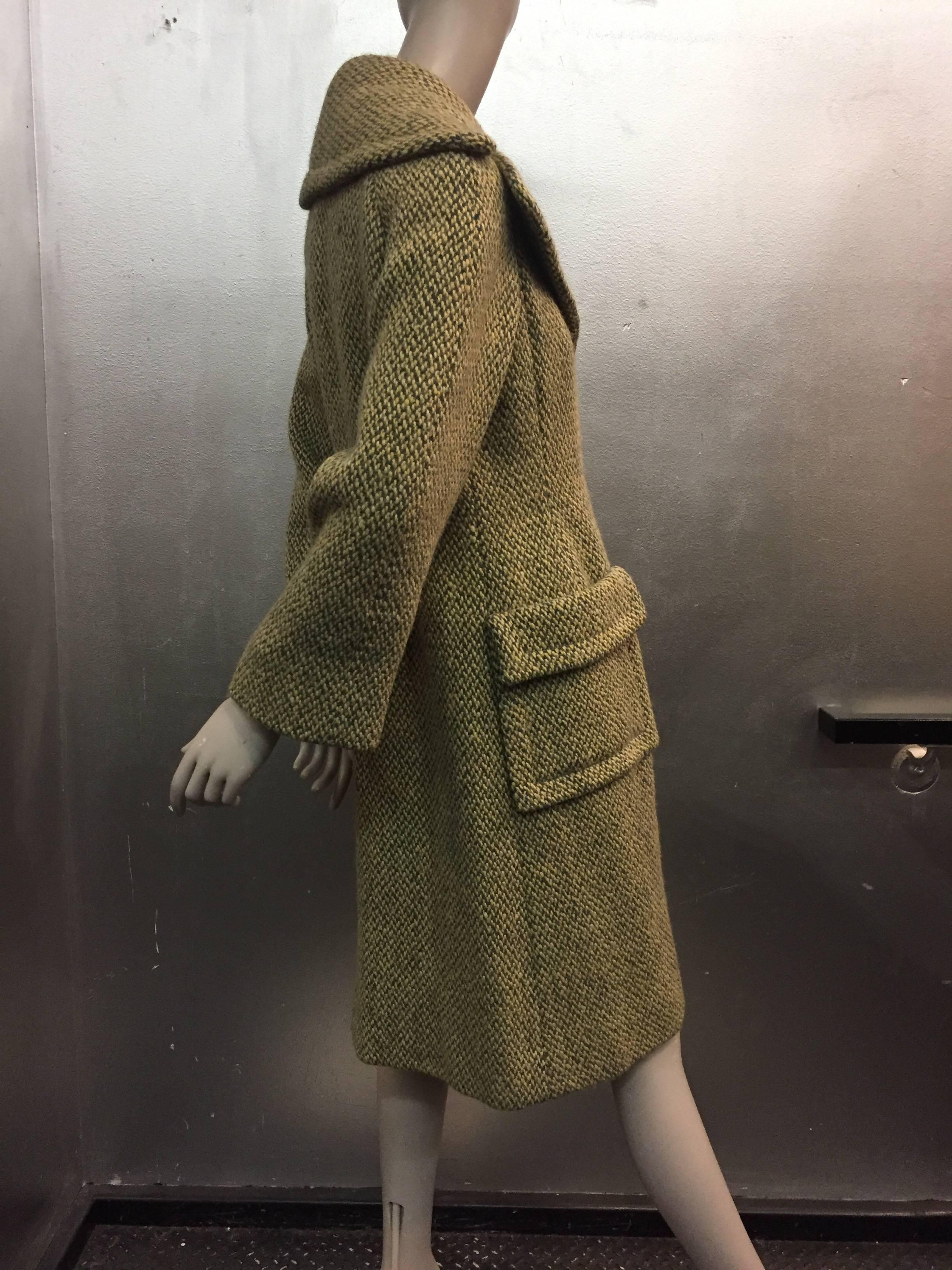 A classic and tailored wool tweed coat with fitted back and large pouch flap pockets.

A large notched collar adds to the drama as well as the custom designed metal buttons by Trigere.

This coat is woven tweed in camel and olive hues it is