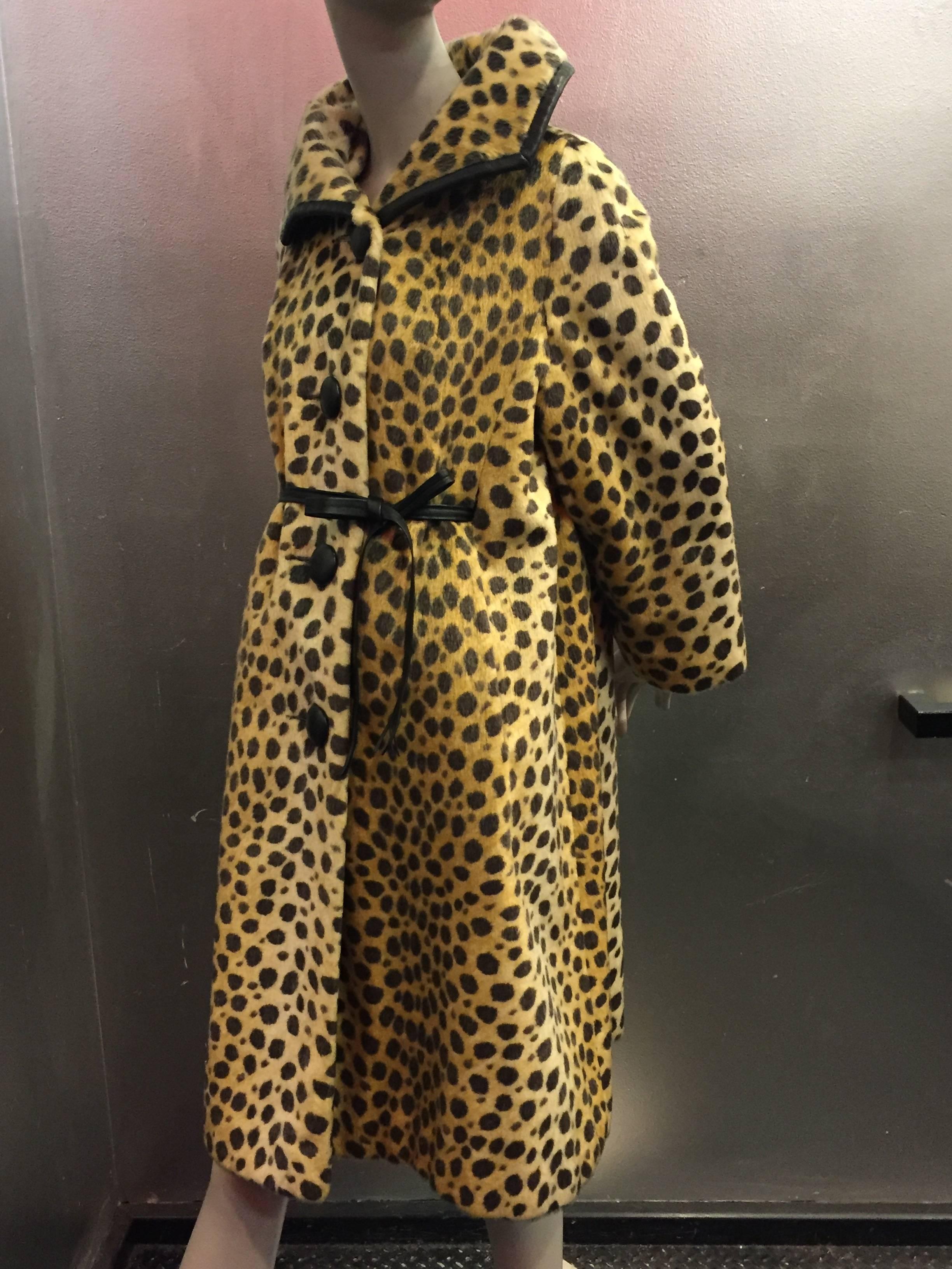 1960s Modela faux fur jaguar print swing coat with leather trim, buttons and front tie. Side slit pockets. Full lining. 