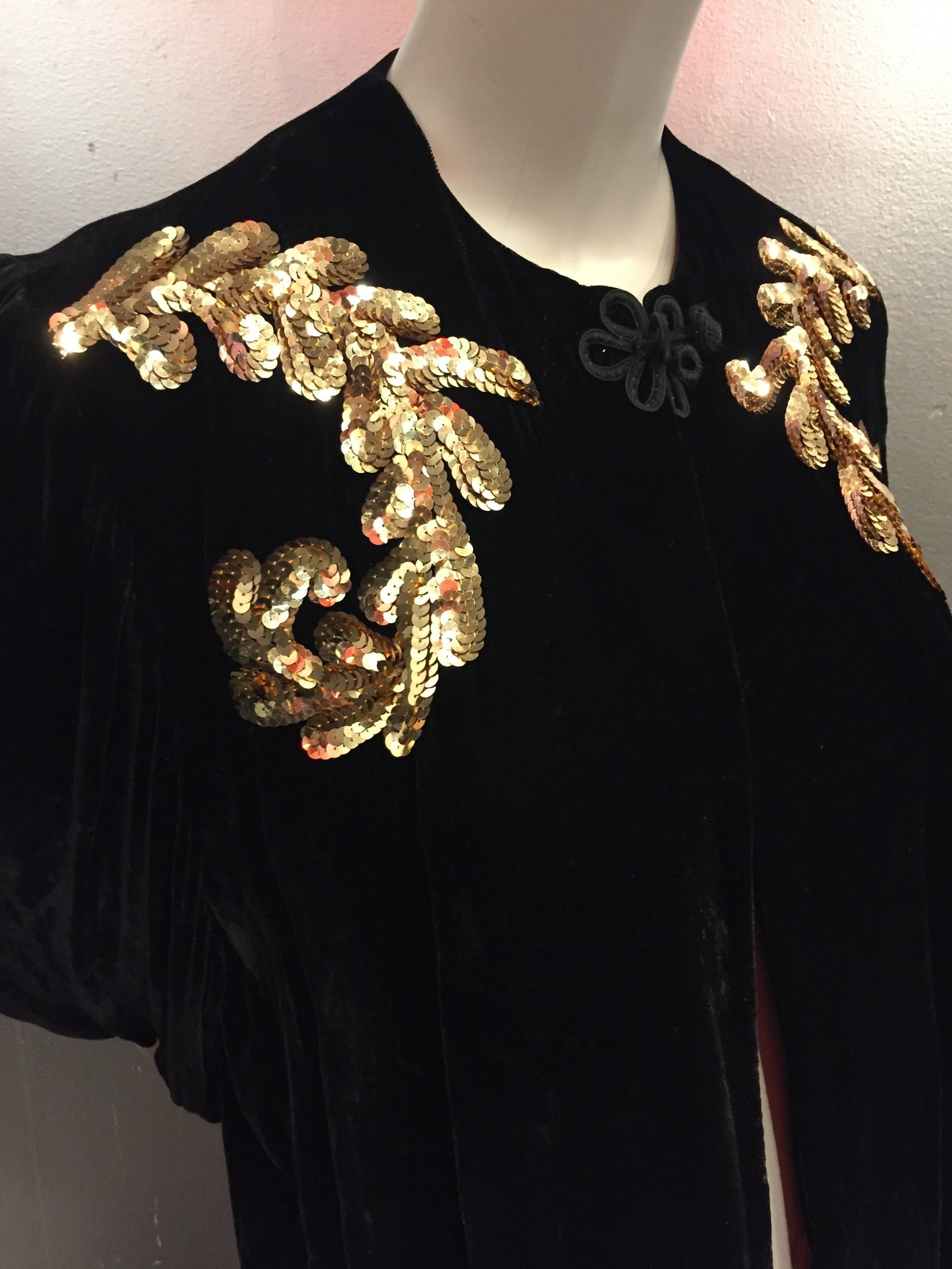 1940s black velvet evening coat with gold sequin leaf appliqué at shoulders and single frog closure.  Shoulder, sleeves and chest are lined in a quilted cream silk for warmth and structure. Full balloon sleeves and smock styling. 