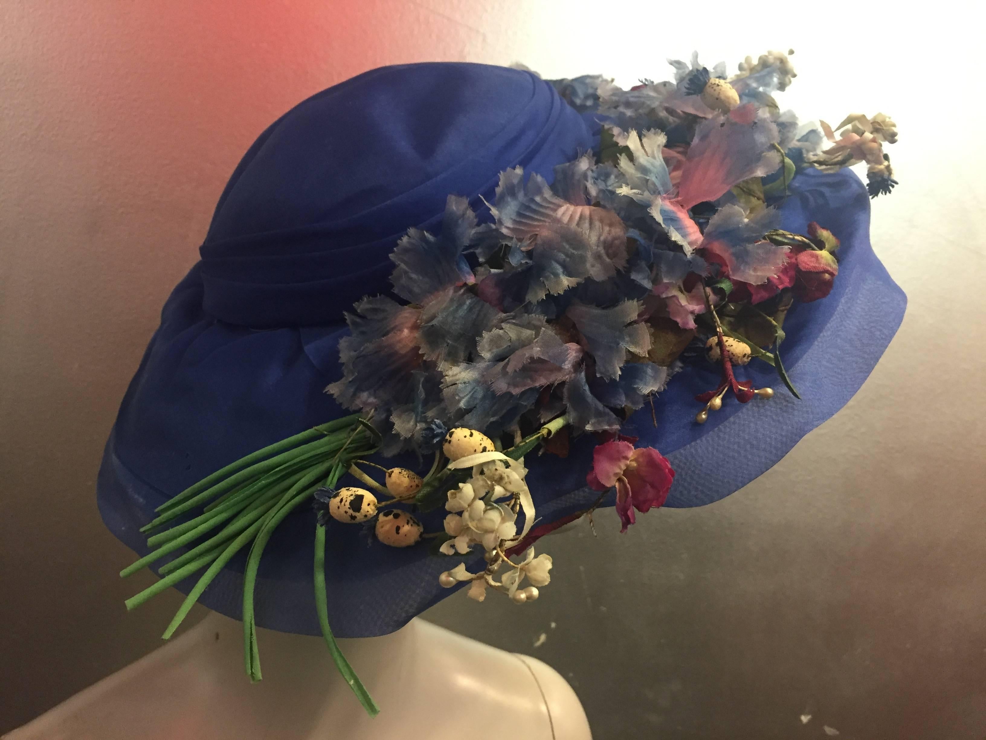 A lovely period hat with a very vintage feel. Featuring an unusual color of blue with various silk wildflowers in pastel colors. 

The crown fits about a size medium. 