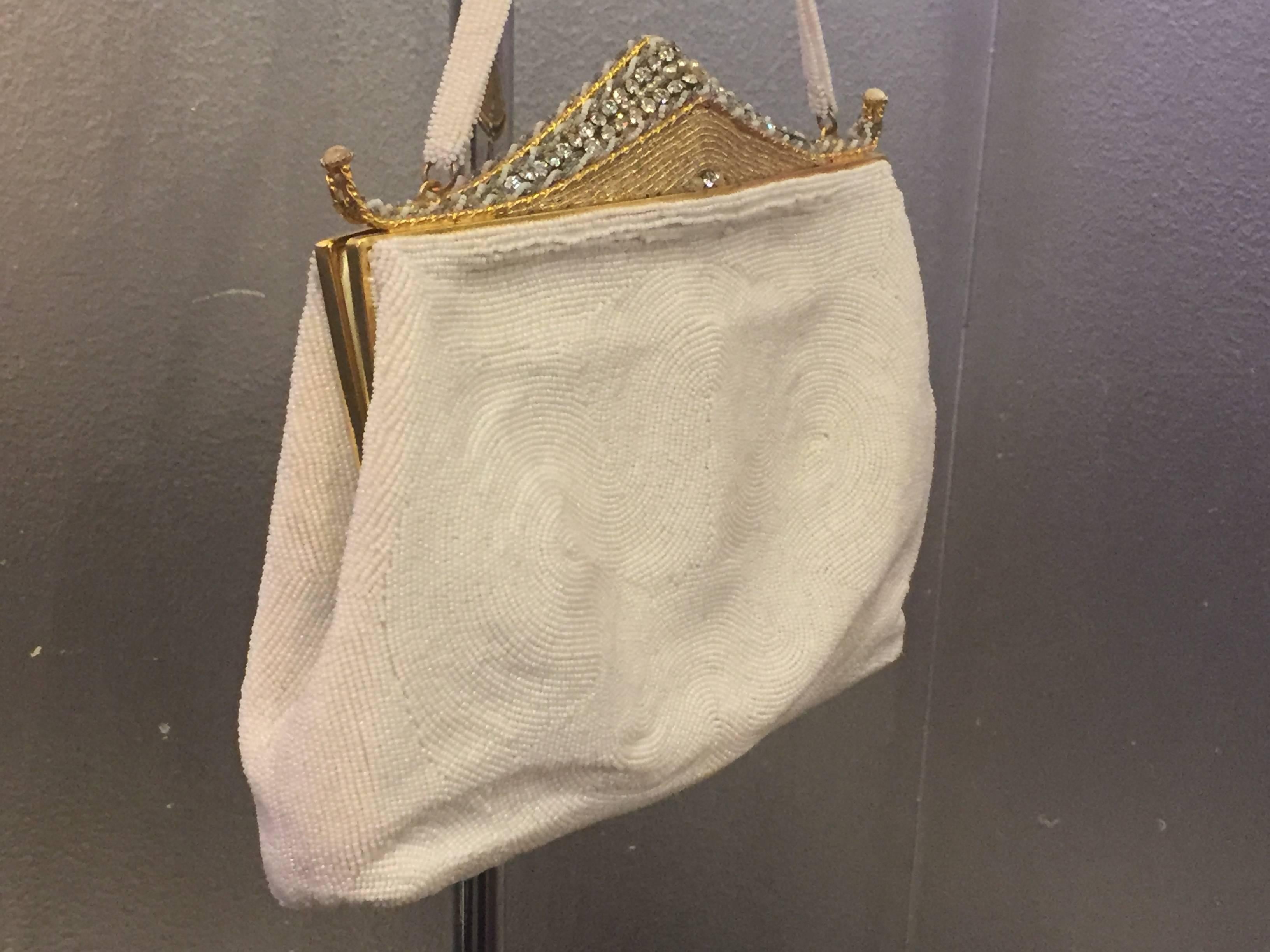 An unusual and whimsical white beaded purse with gold beaded and jeweled pagoda frame. A fan-shaped clasp opens to a white silk lining with pocket and coin purse. The white beading features a subtle scallop pattern. Most likely French. 

Length - 8