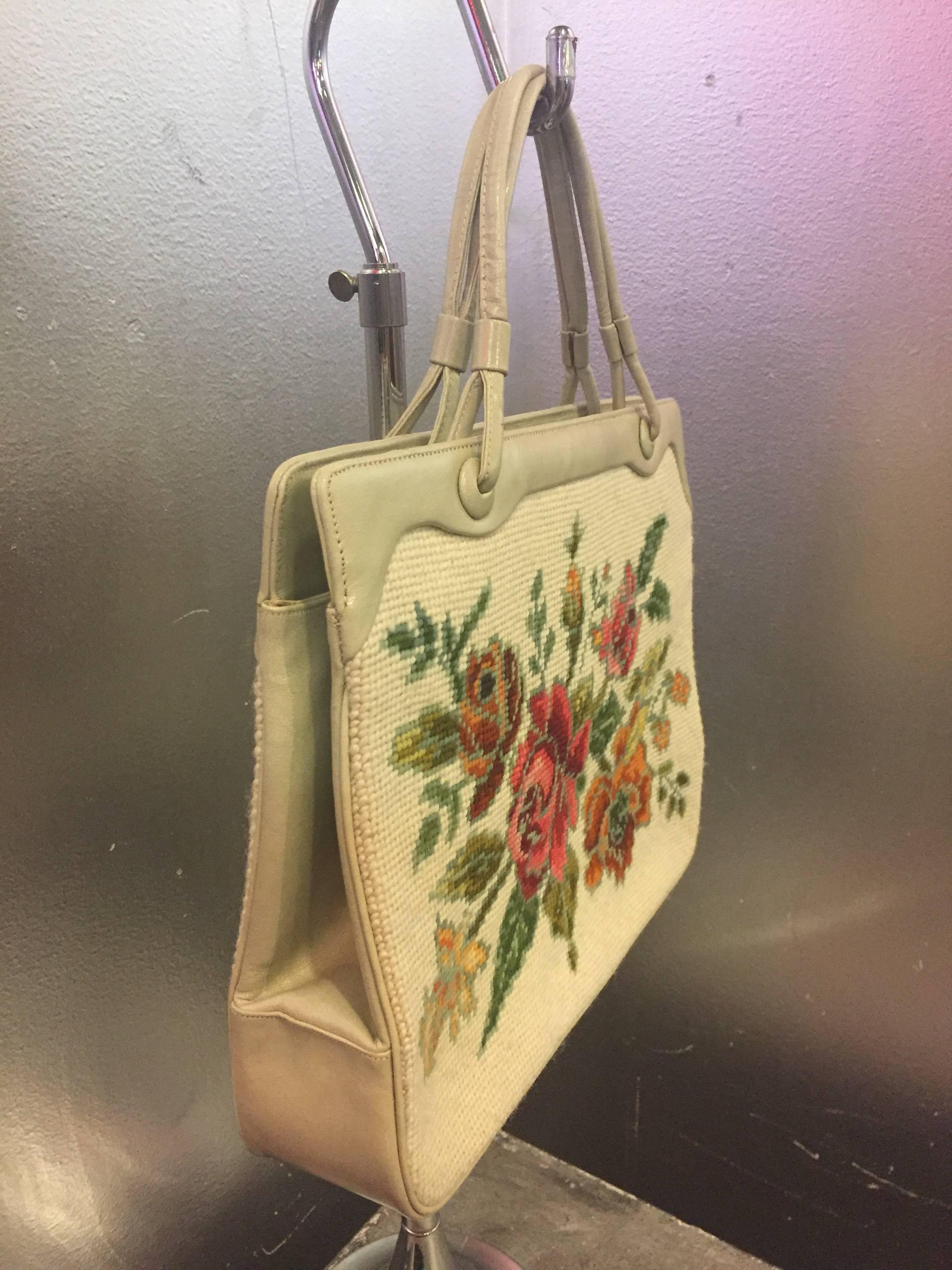 A stunning bouquet of colorful needlepoint roses set against bone leather trim. Bag features double-rolled leather handles with brass feet. Interior is cream grosgrain in impeccable condition. 