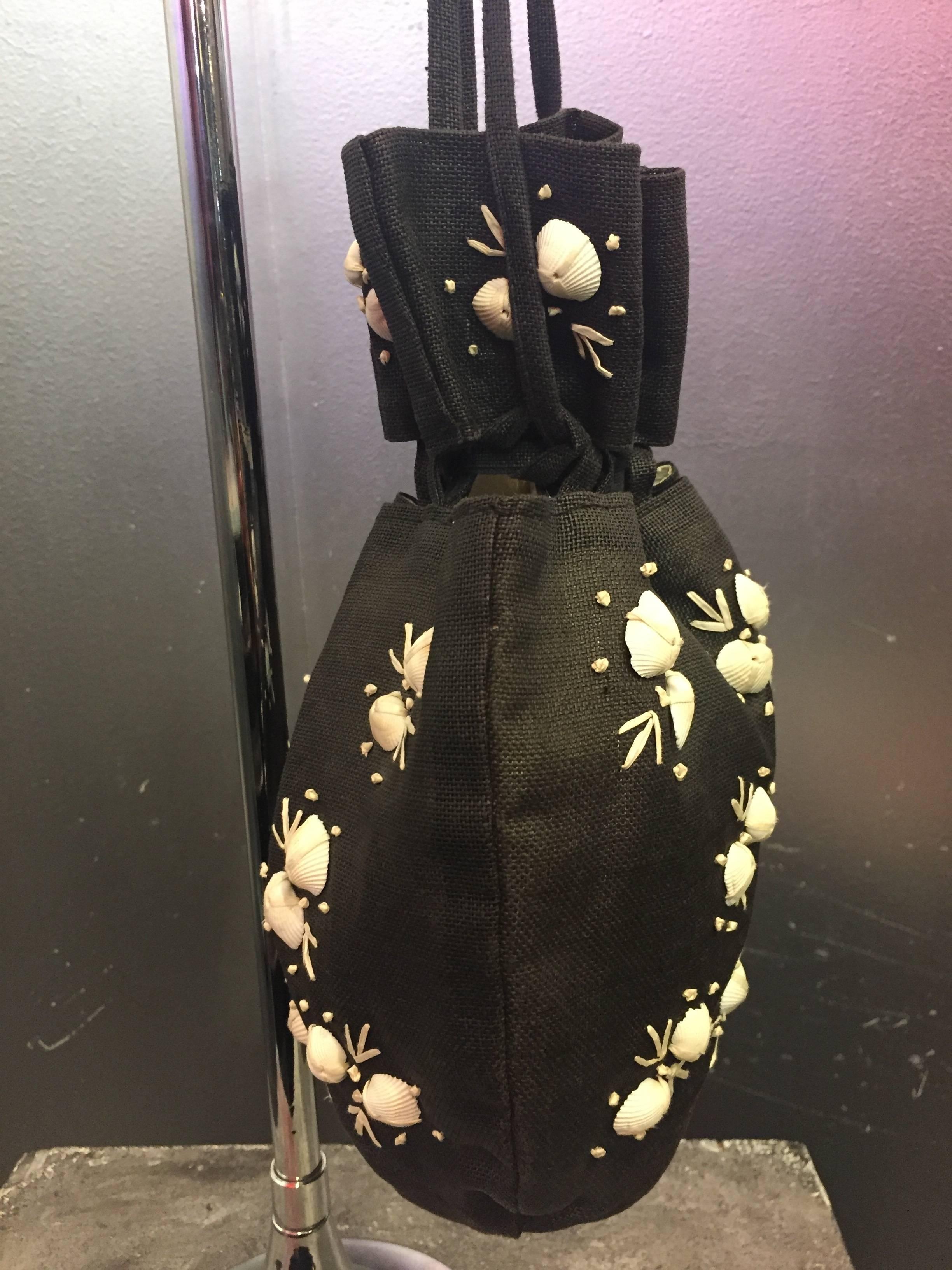 A wonderful drawstring style black straw pouch bag made of finely woven black straw. The exterior is adorned with real seashells and embroidery. Perfect for summer and resort attire. 