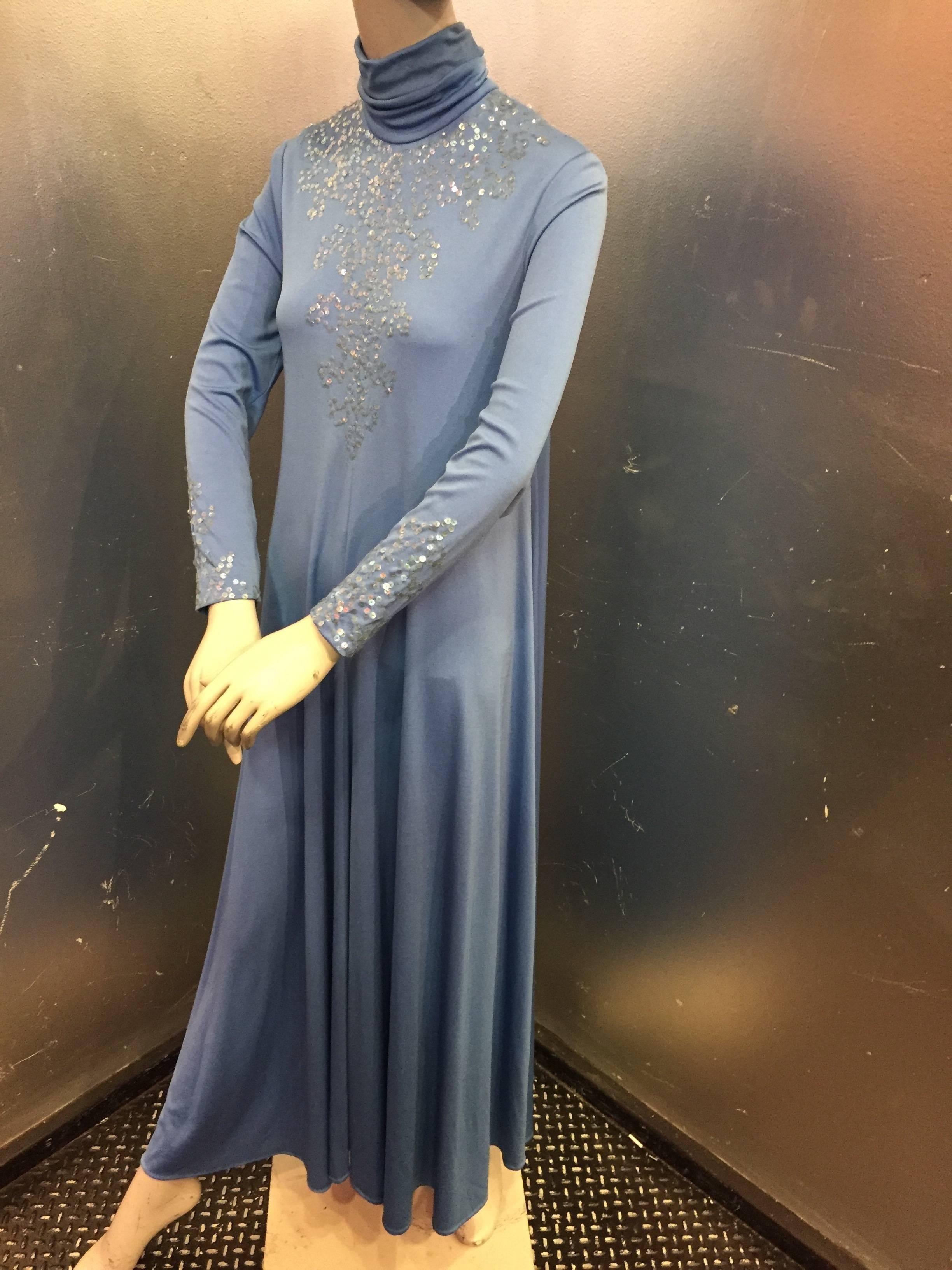 1970s The Gilberts for Tally cornflower blue jersey maxi dress with iridescent sequins covering the shoulders, front and back of bodice.  Back zipper and a high rouched neck. Shoulders and arm holes are fitted and then it flares gracefully into a