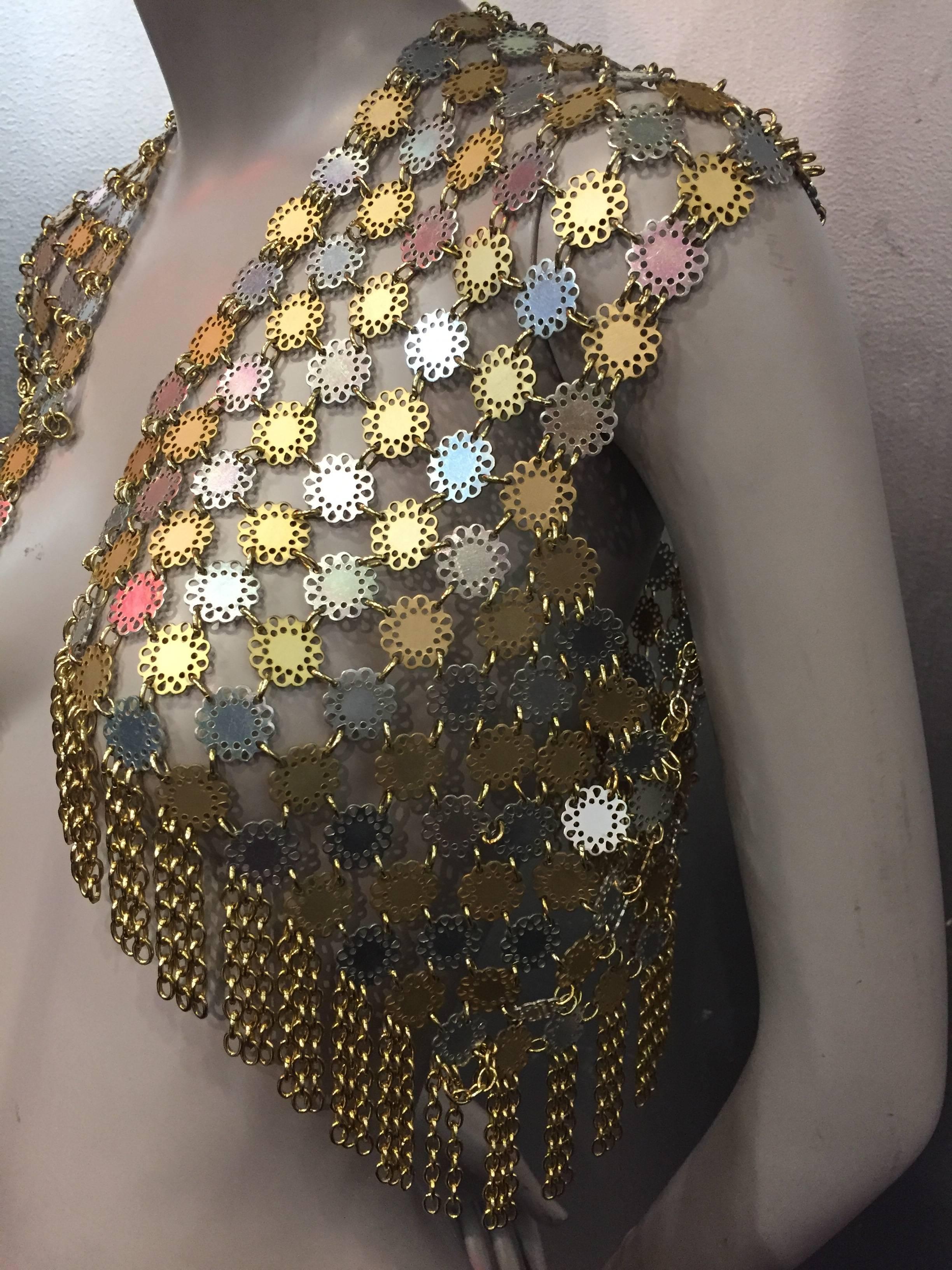 Paco Rabanne was widely considered the enfant terrible of French fashion. 

This iconic vest of metal discs is reminiscent of 60's mod flowers. Linked in aluminum and gold, the two-tone metallic color combination adds a vibrant feel to the chainmail