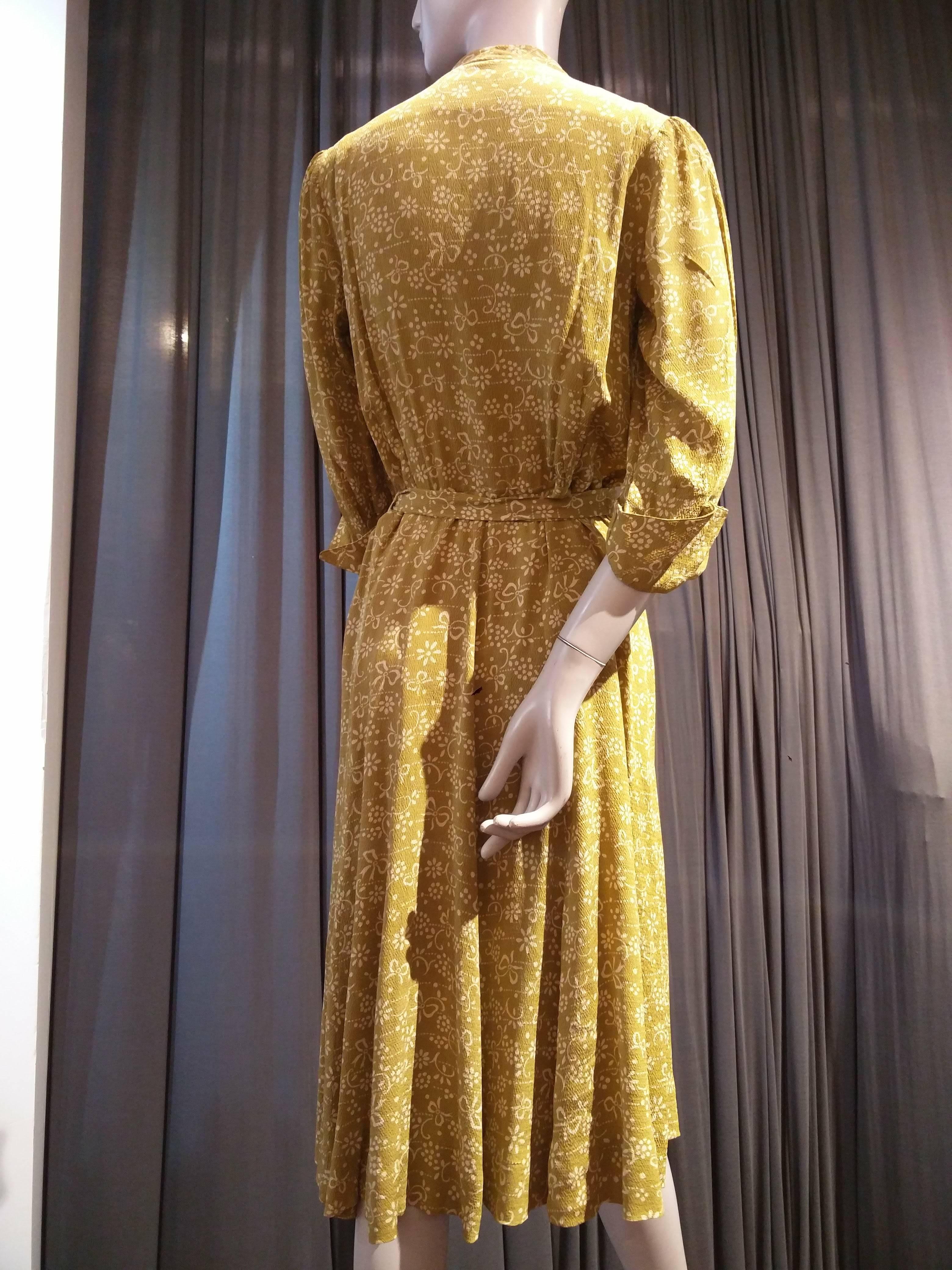 A fantastic and hard-to-find iconic 1940s Eisenberg and Sons gold and white floral print lightweight silk crepe dress: fitted shoulders with blouson bodice and sleeves with gathered cuff.  Faux pocket flaps at top of bust. Eisenberg and Sons were