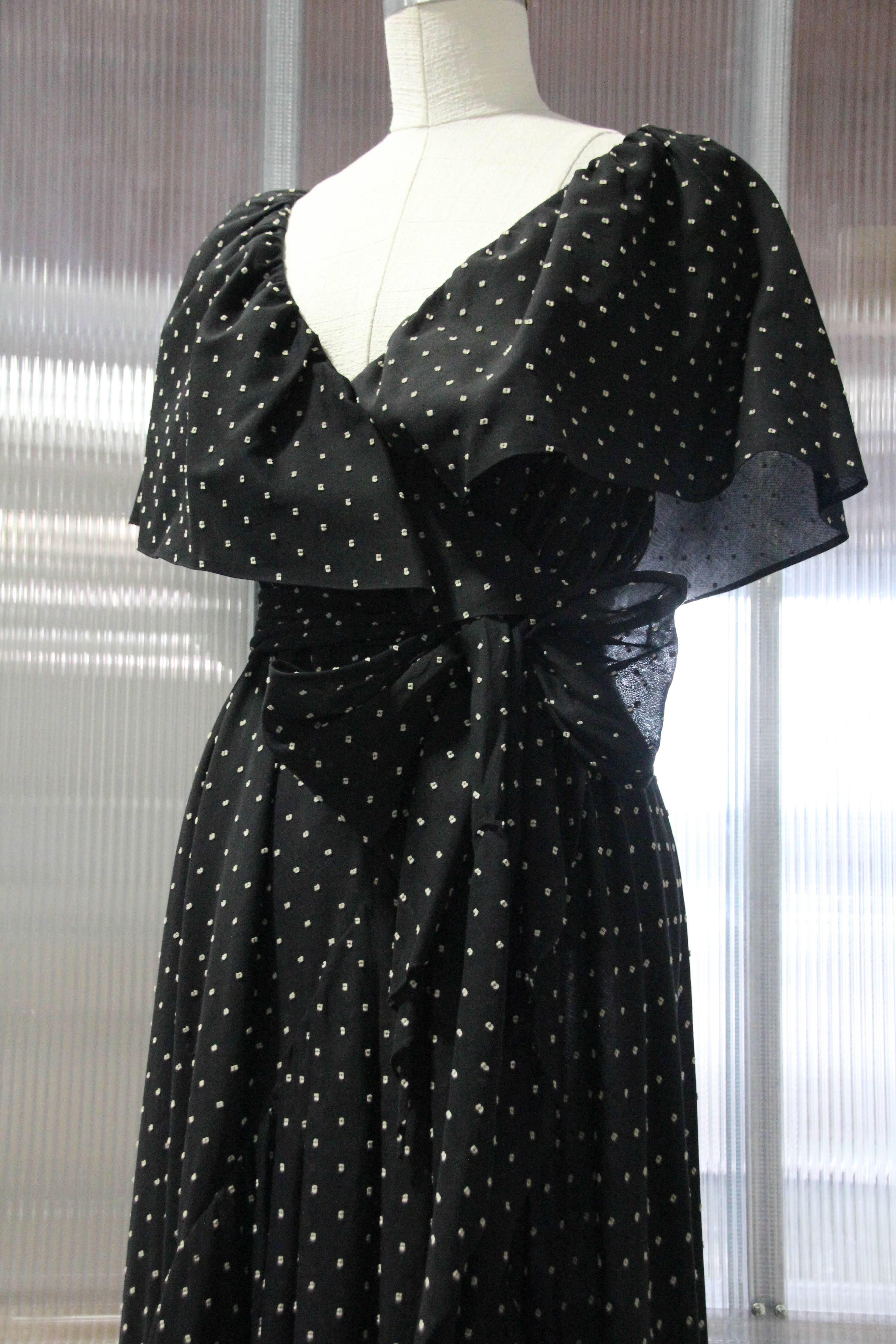 A beautiful 1980s Halston dotted cotton voile wrap-style gown with ruffled collar and fitted waist. Structured inside for support with a waist band grosgrain ribbon. Bowed sash at waist. Sexy leg exposure.
Iconic Halston construction and style!