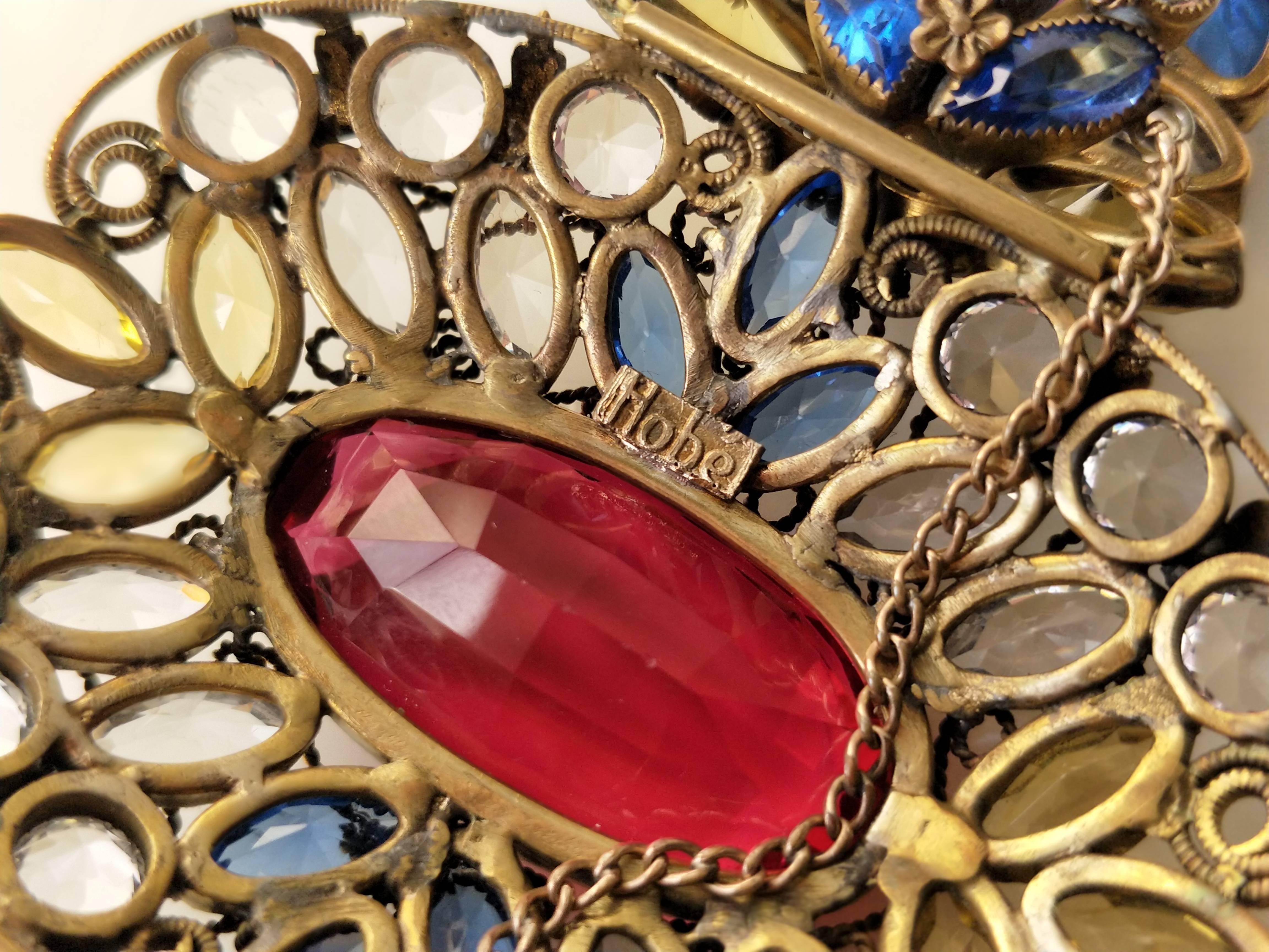 1940s Hobe, stained-glass-effect hinged cuff bracelet with a large central ruby red crystal and multi-colors throughout. Open back settings. Two articulations with hinges on each side of center faux ruby.  Center medallion measures 3 inches.  Washed