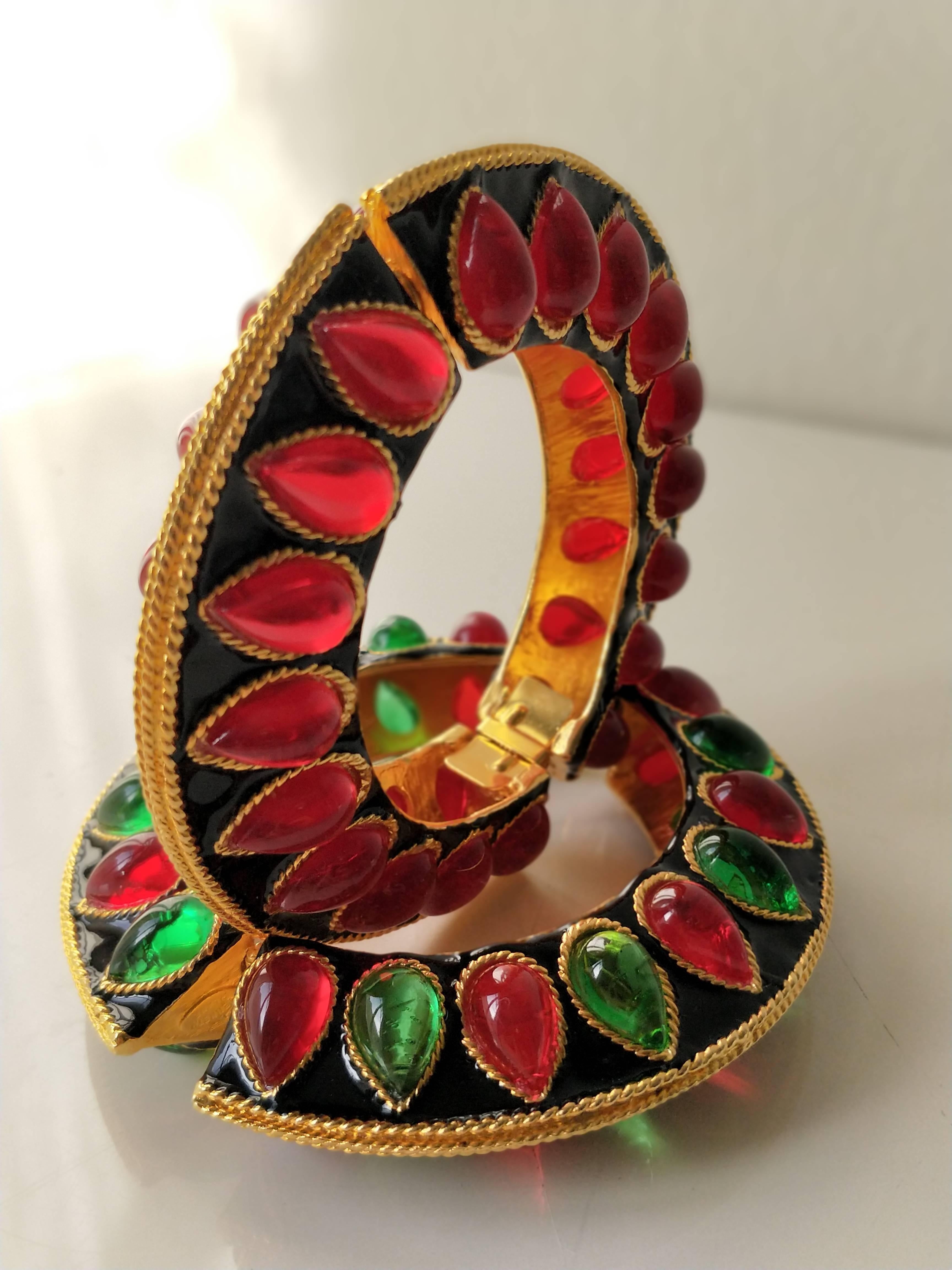 A pair of 1980s Kenneth J. Lane Anglo-Indian style enamel and poured glass cuff bracelets. Spring-loaded hinge. Watermelon seed shaped poured glass insets in green and red. 7 inch interior measurement.