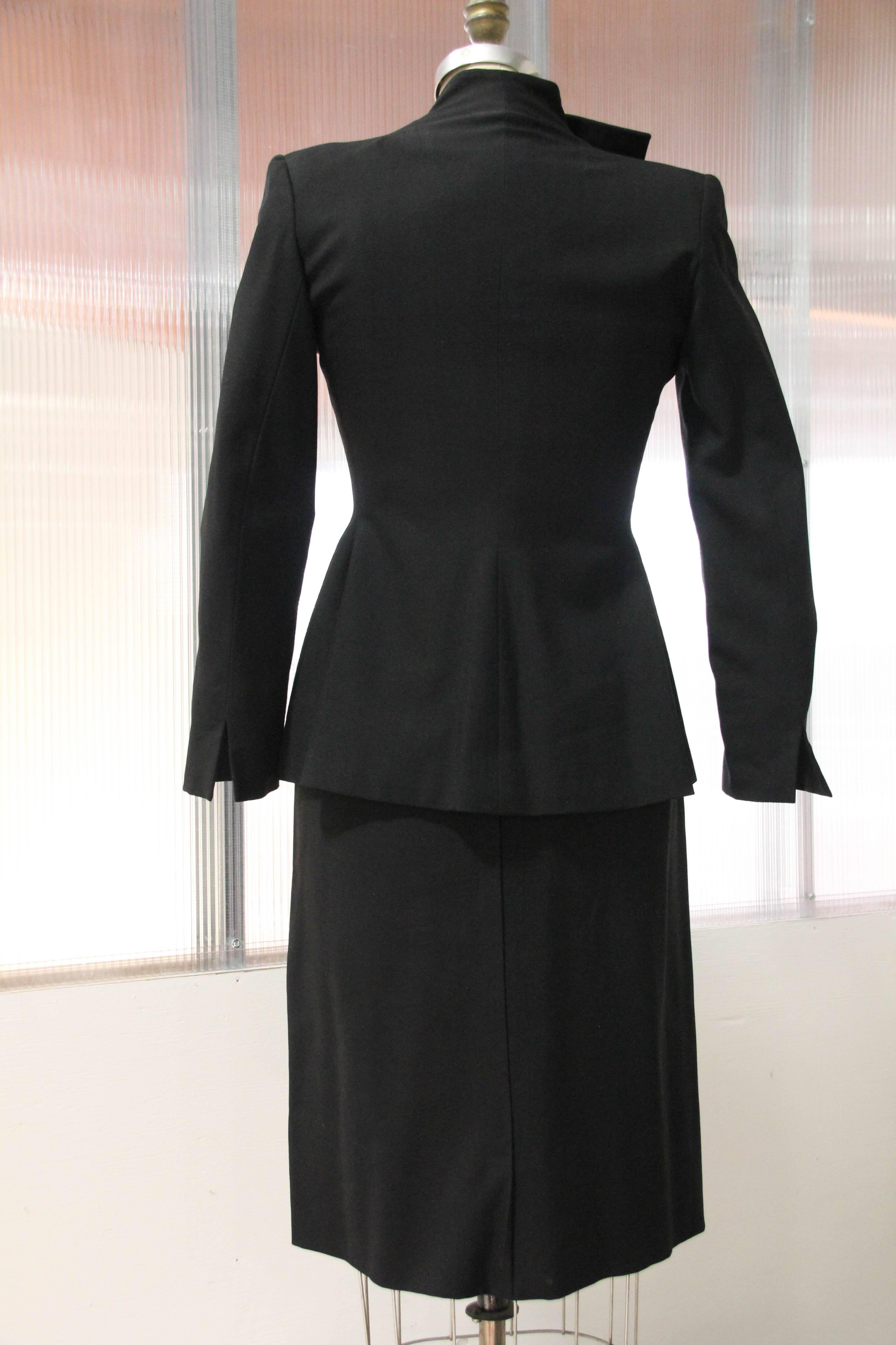 A rare 1940s Irene skirt suit in black wool with Avant Garde geometric overlapping reverse-button front closures.  Skirt is a slight A-line, below the knee style. Shoulders are strong and all the original covered buttons are present.  Jacket is open