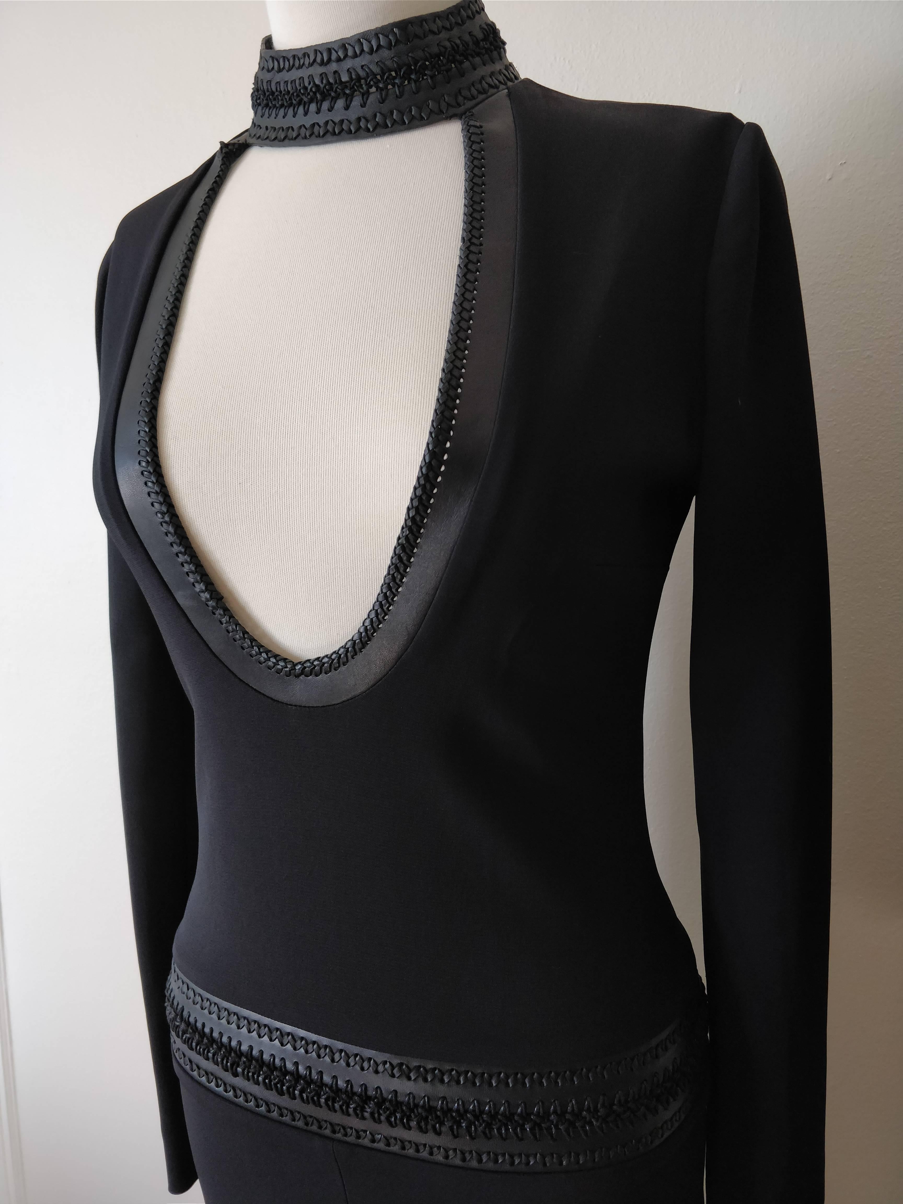 A Tom Ford Boho-chic 1960s-inspired black knit dress with leather banding and braid at hips. Choker-style neckline with scooped out decolletage edged in braided leather.  Zippered back. Never worn. 