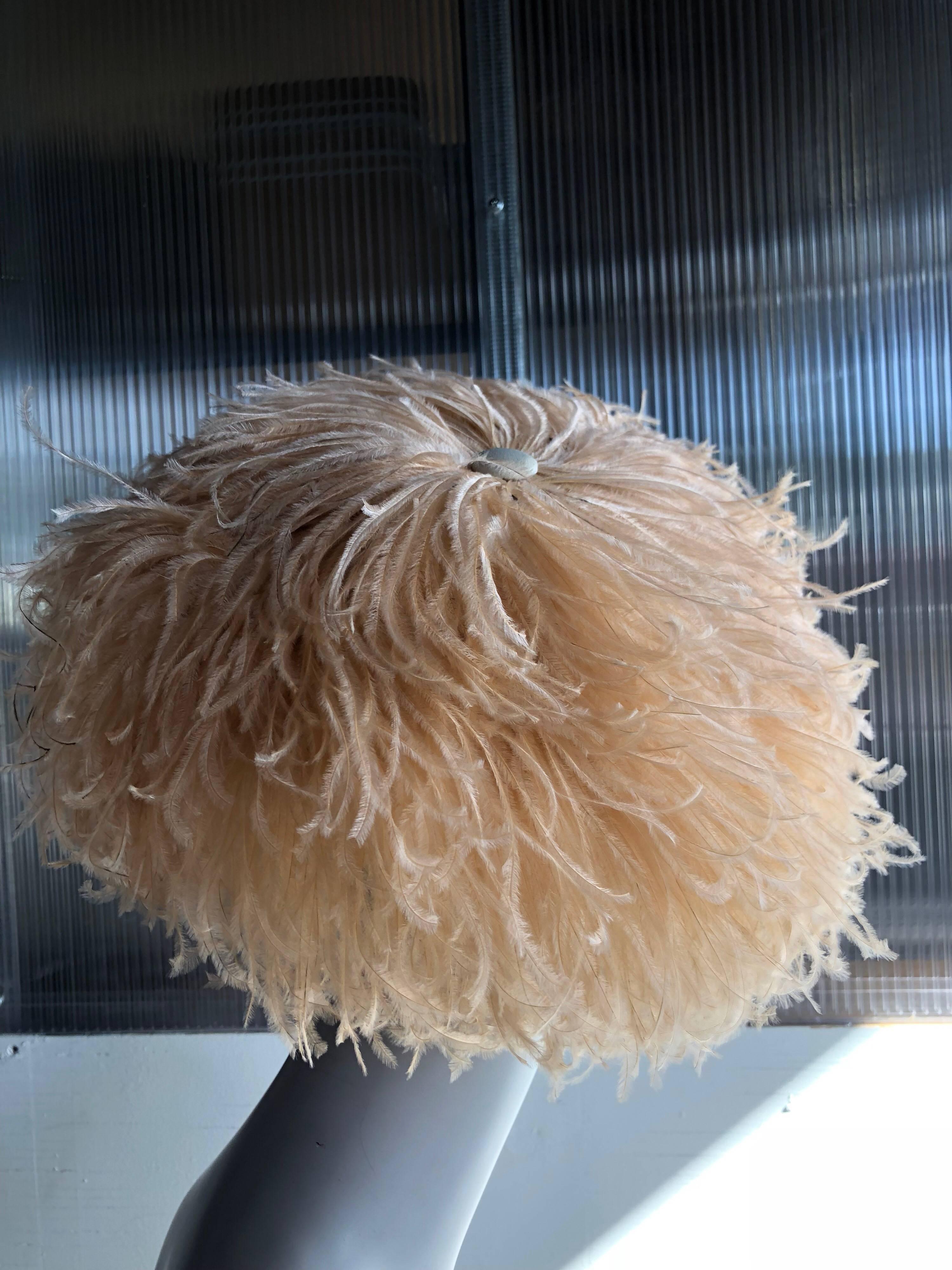A beautiful 1950s Lora peach-toned curled ostrich feather cocktail hat:  The underlying structure of the hat is a saucer shape with a one-size-fits-all structured crown.  The luxurious peach ostrich feathers are arranged in a radial design from the