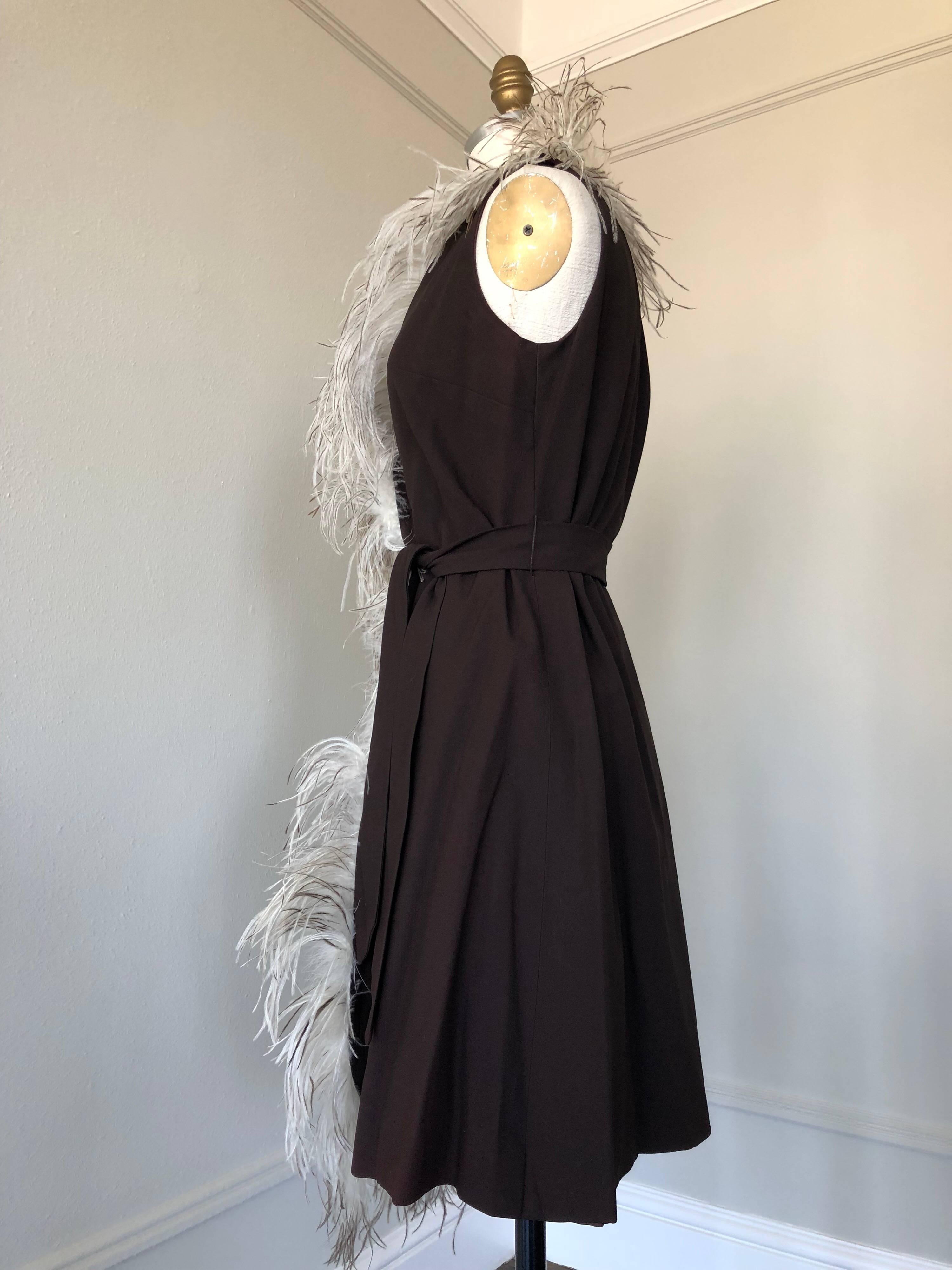 1960s Mr. Gee black crepe knee-length wrap dress with asymmetrical lush natural ostrich feather trim around neck, down front edge and part of hem.  Original belt included. 