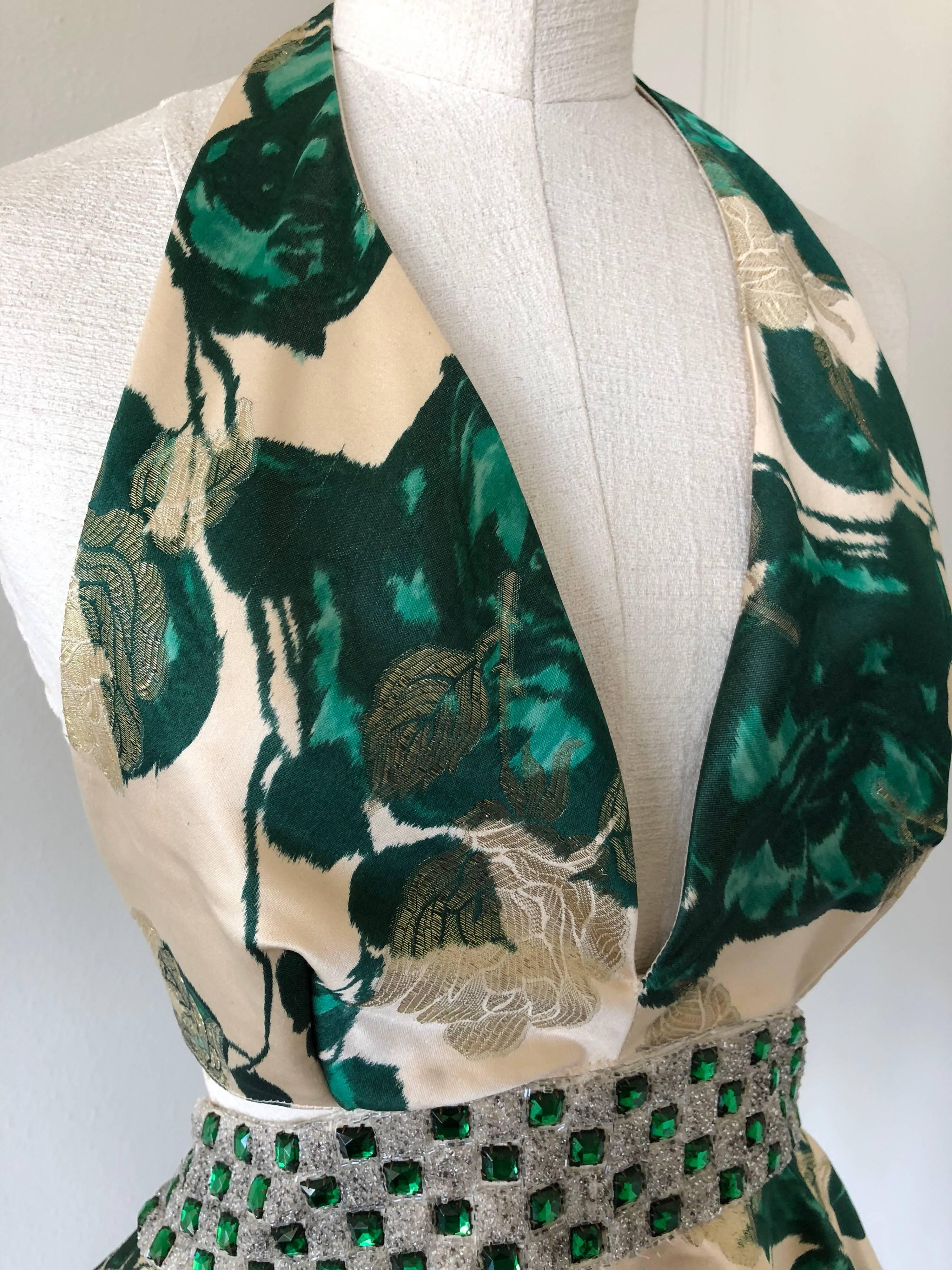 1950s Spring emerald water color floral brocade halter top with peplum.  Back and neck tie with zipper and peek-a-boo panel.  Waistline is embellished with silver lame band studded in emerald green rhinestones! 
