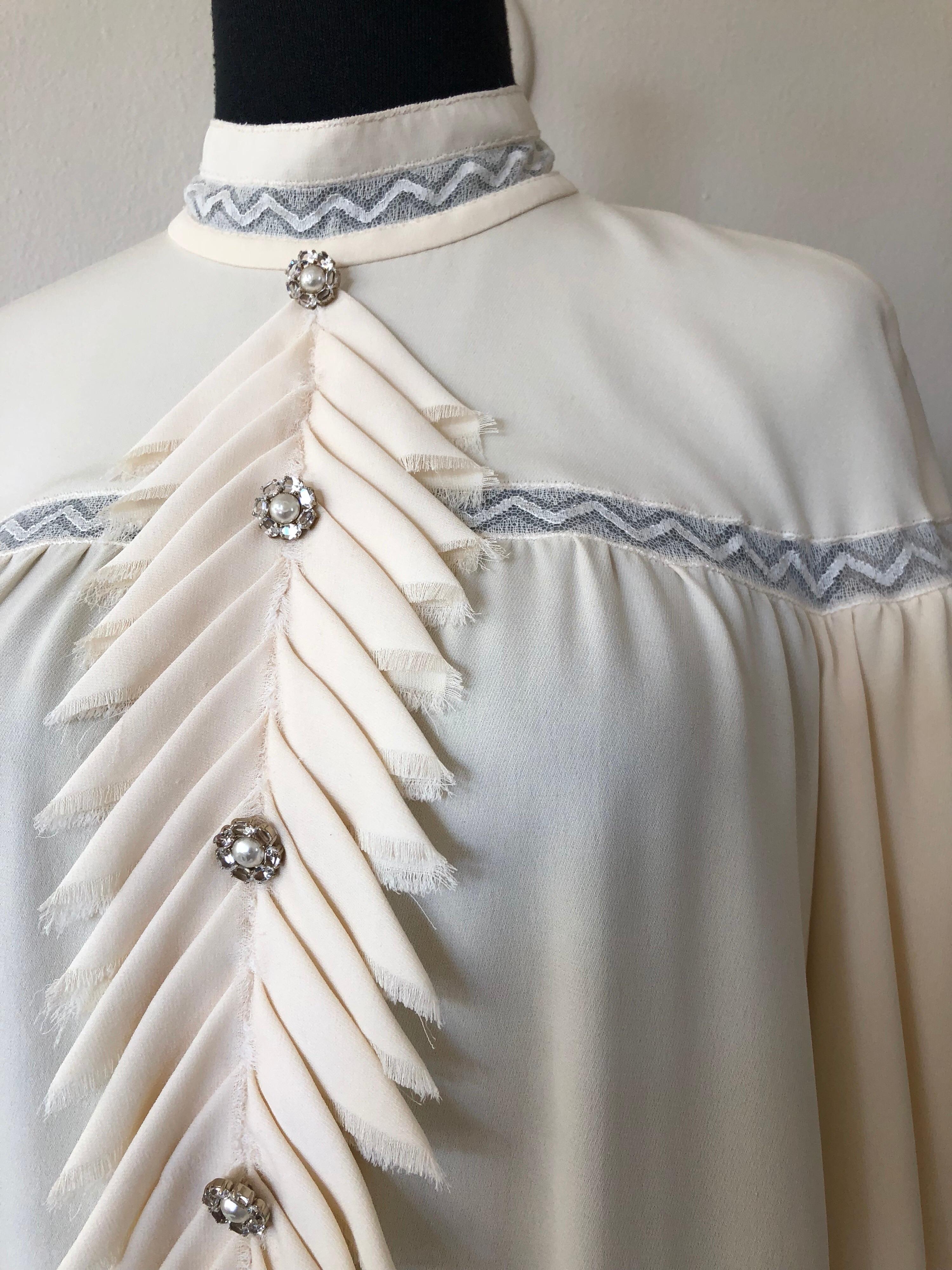 An incredible Chanel cream silk blouse with banded collar and extravagant multi-layered poet-style sleeves!  Layers and layers of mixed silk lace and ruffle cascades.  Hems are trimmed in lace. Original Chanel logo buttons down front ruffle bib and