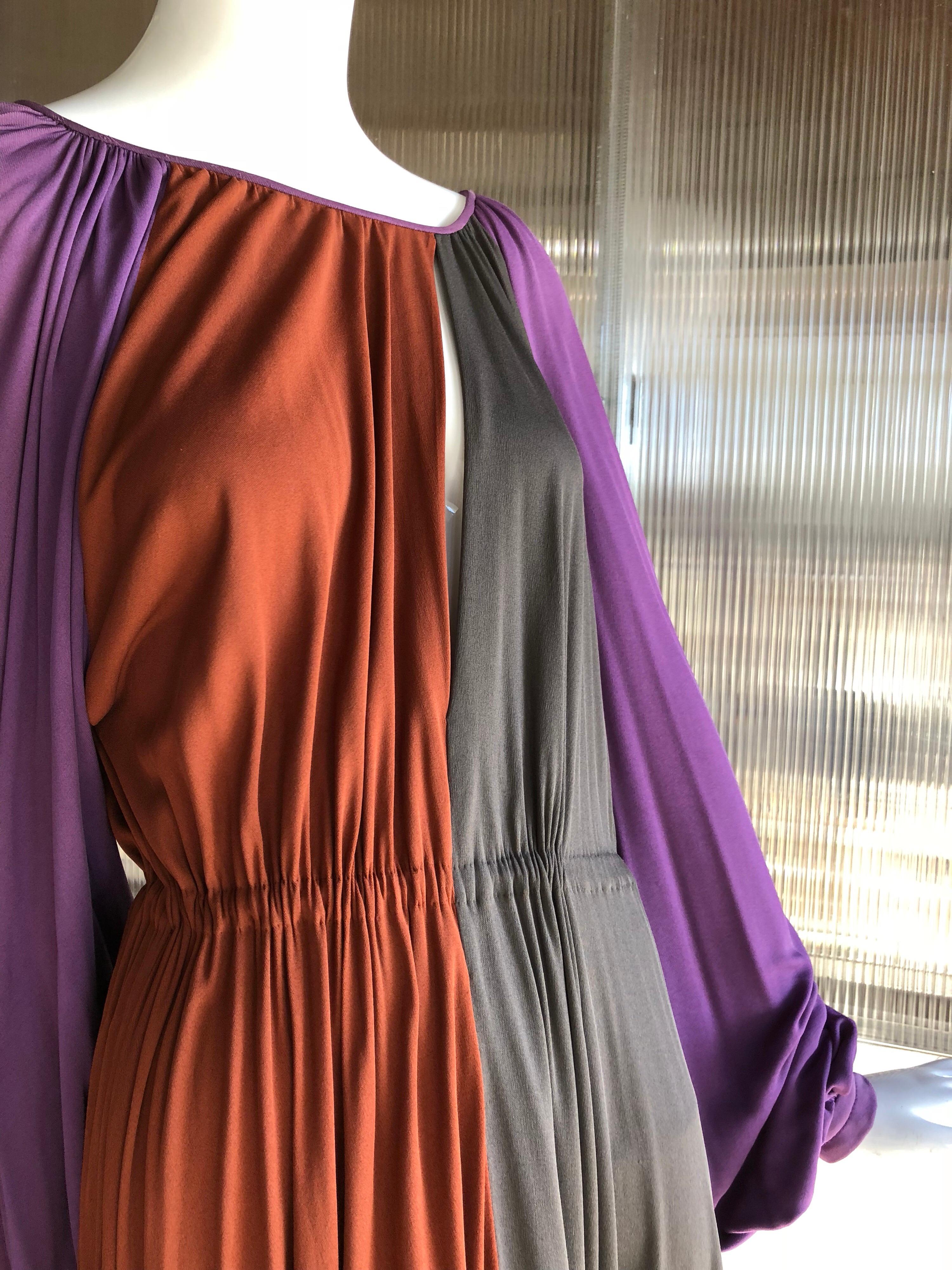 1970s James Galanos streamline and sleek draped silk jersey calf-length disco dress in color-blocked purple, rust and taupe. Asymmetrical keyhole neckline enhance this couture quality custom made piece. 
Beautifully draped balloon sleeves a