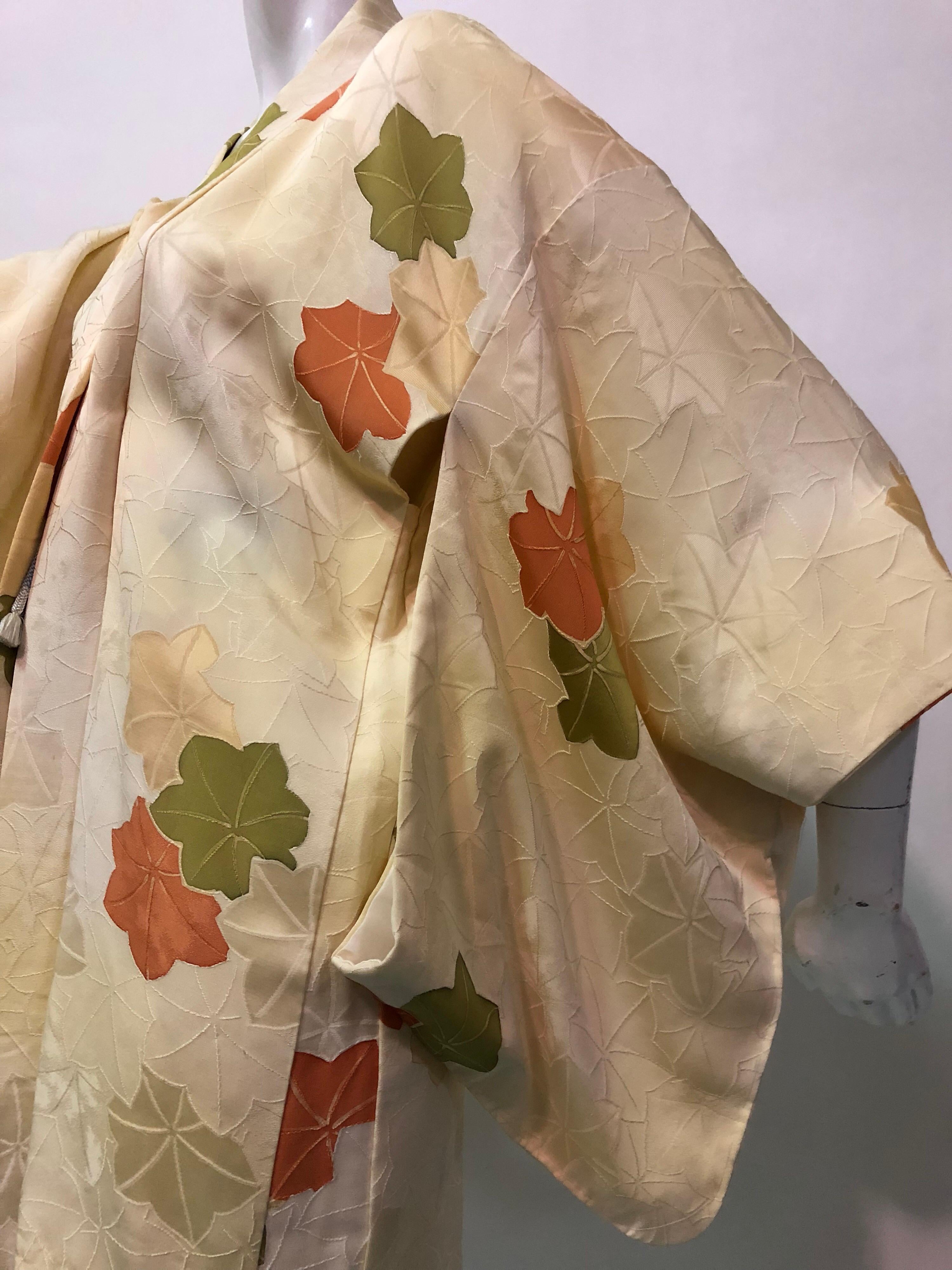 Un meraviglioso kimono giapponese vintage in seta stampata, di colore crema con motivi floreali color oliva e ruggine. Stile tradizionale con taglio a kimono, maniche a vista e chiusura frontale con lacci. 
Condizioni meravigliose e ottimo per