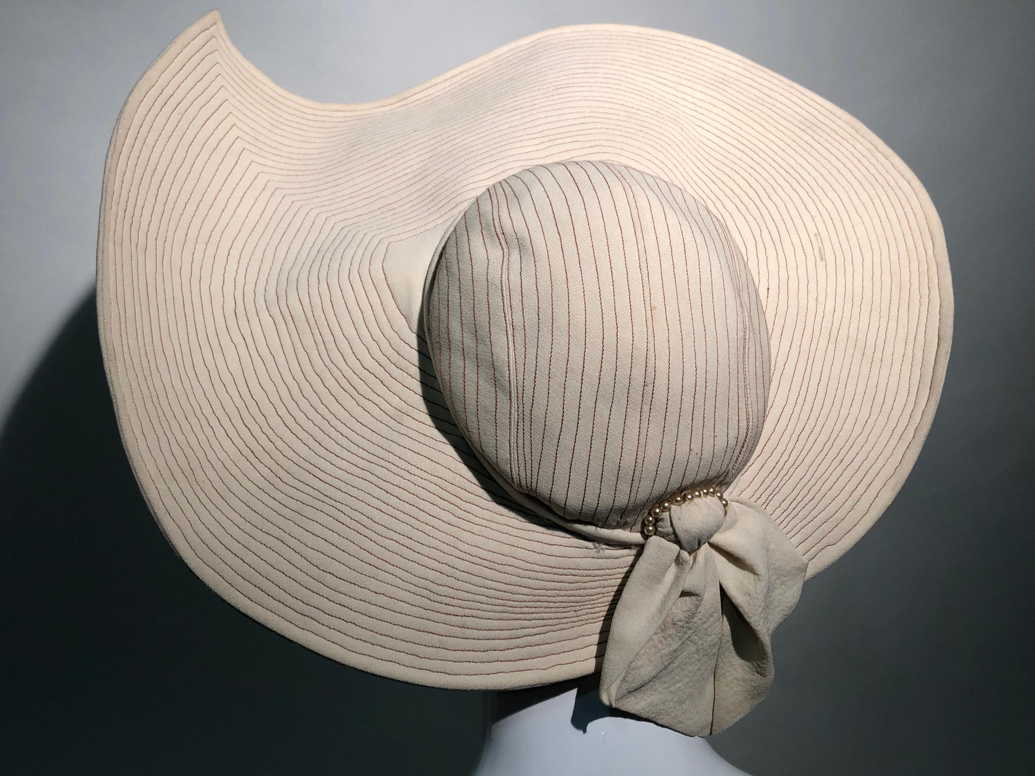 An uniquely shaped very large and dramatic 1930s Lucille Morgan summer crepe hat in eggshell with tan trapunto stitching covering the entire hat to give it structure. An unusual paisley shaped brim is curled up on one corner. One size fits all as