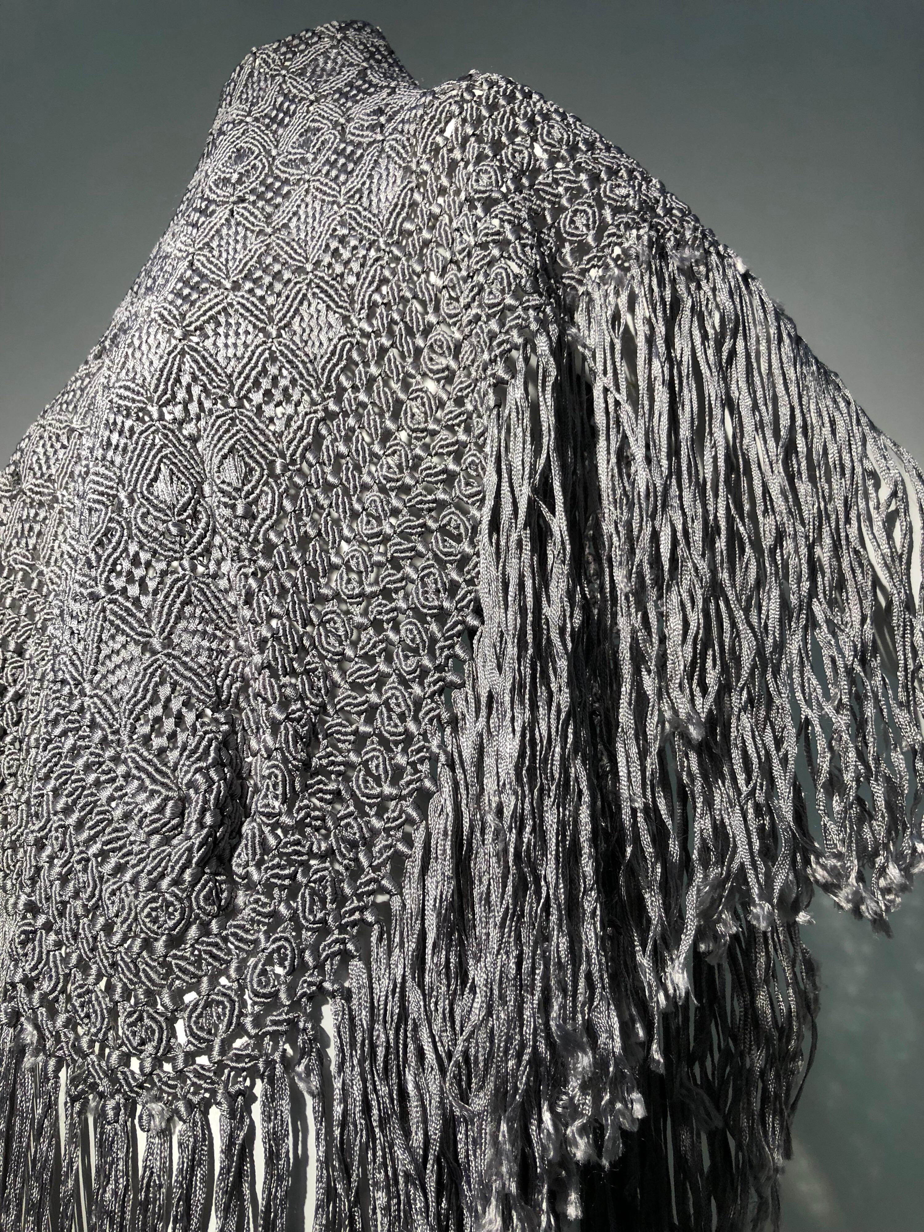 Un beau châle en ruban macramé frangé en soie et rayonne gris tourterelle de I. Magnin des années 1970. Forme triangulaire avec longue frange luxueuse sur 2 côtés.  
