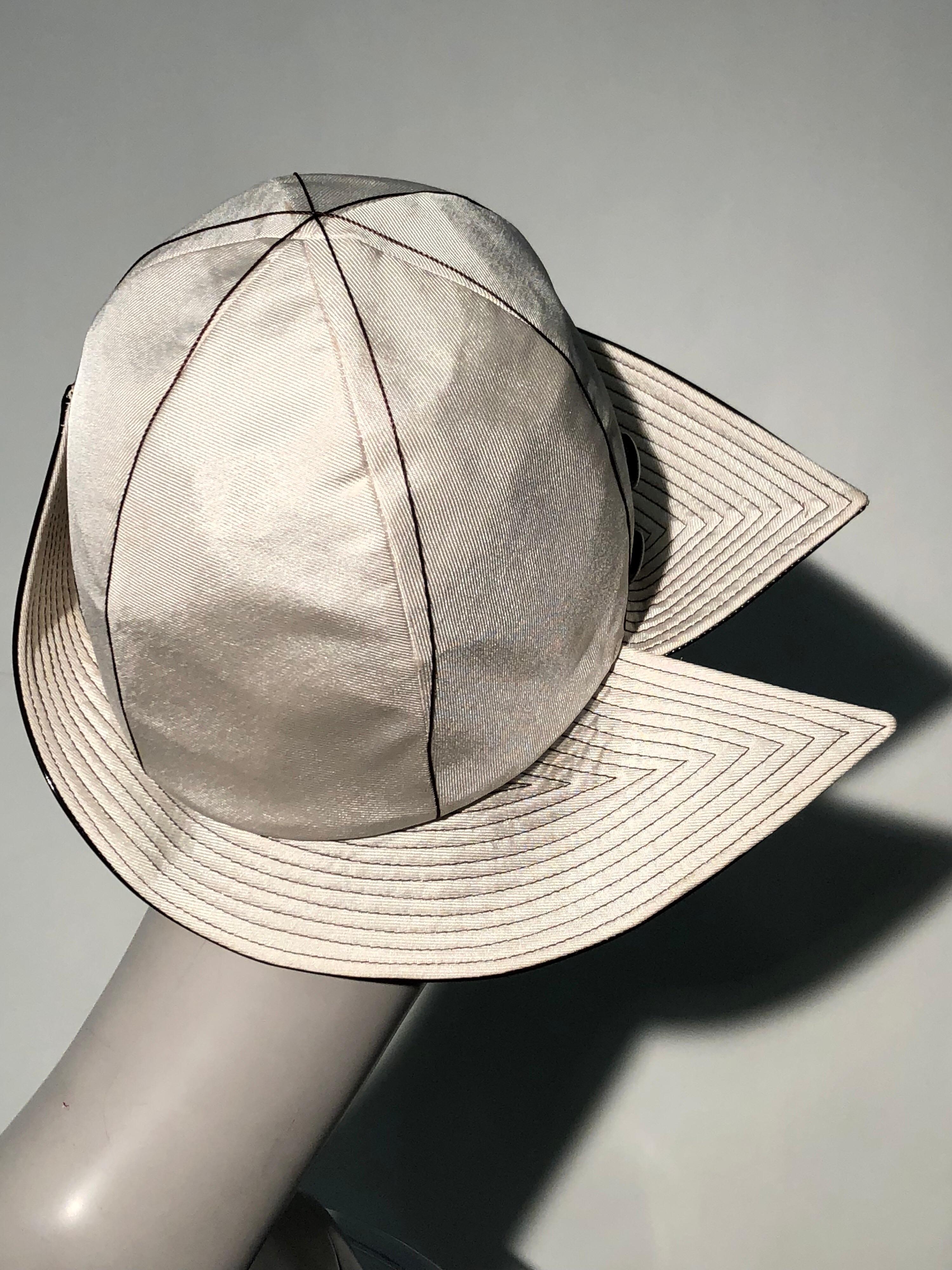 A fabulous 1960s Mr. John ivory faille dome-shaped Mod style hat with wide trapunto-stitched brim in brown patent leather. Brim is split at side. Two brown patent leather buttons adorn the side. A surprisingly cheery floral lining inside.
