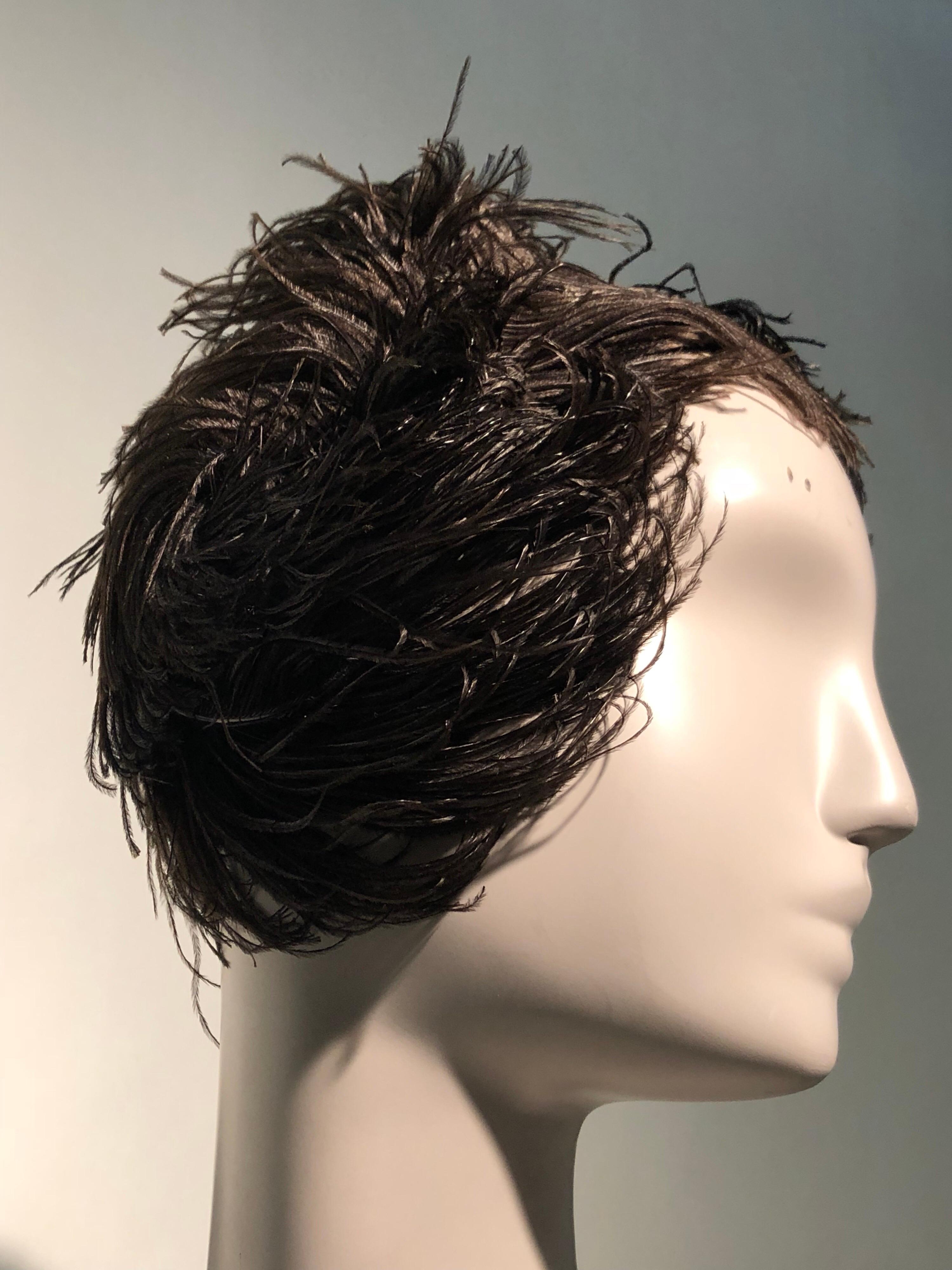 A beautiful 1950s Christian Dior ballet-inspired black ostrich feather cocktail hat that swirls around the head dramatically. Rather wig-like at the back of the head and at neckline. Worn toward crown.