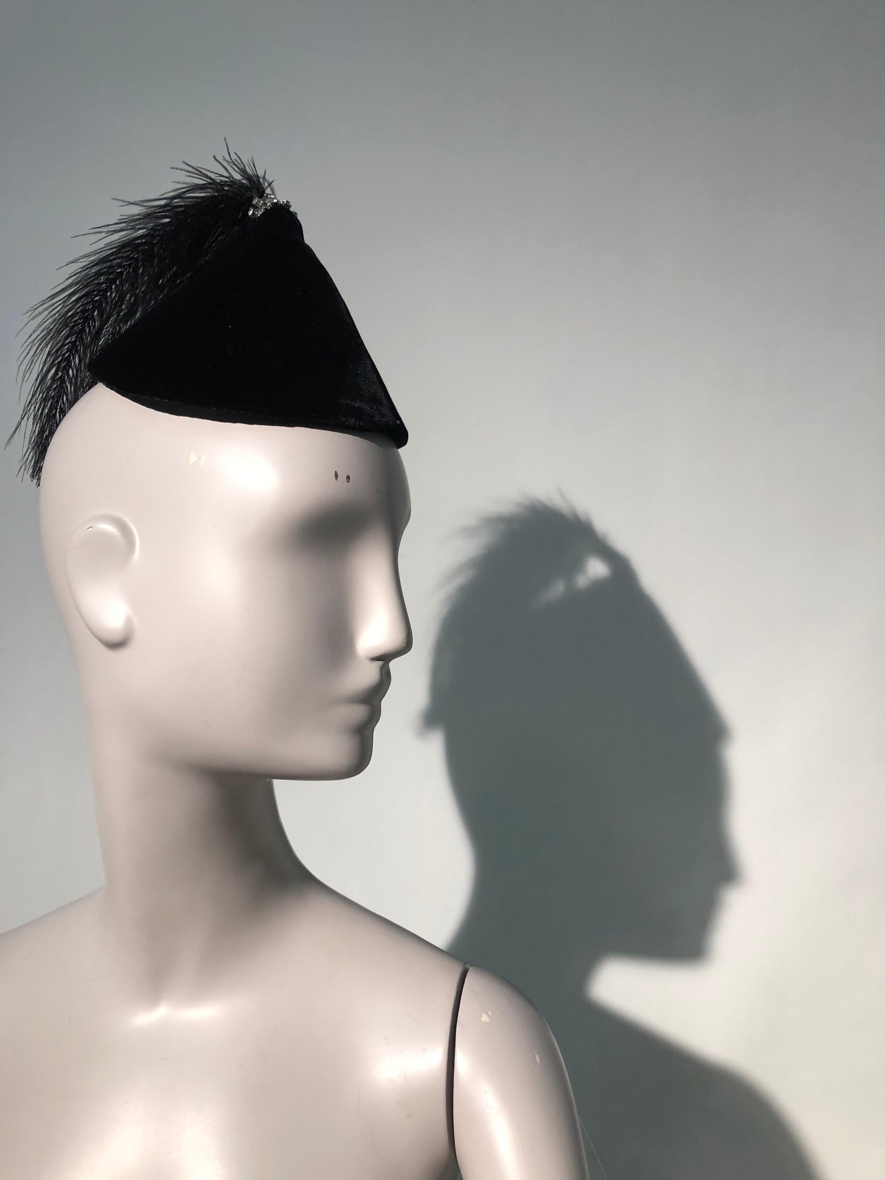 A fabulous 1950s Raymond Hudd Originals black velvet cocktail hat with egret feather and rhinestone trimmed tassel. Petite in scale, this structured conical hat attaches with combs that are original.  