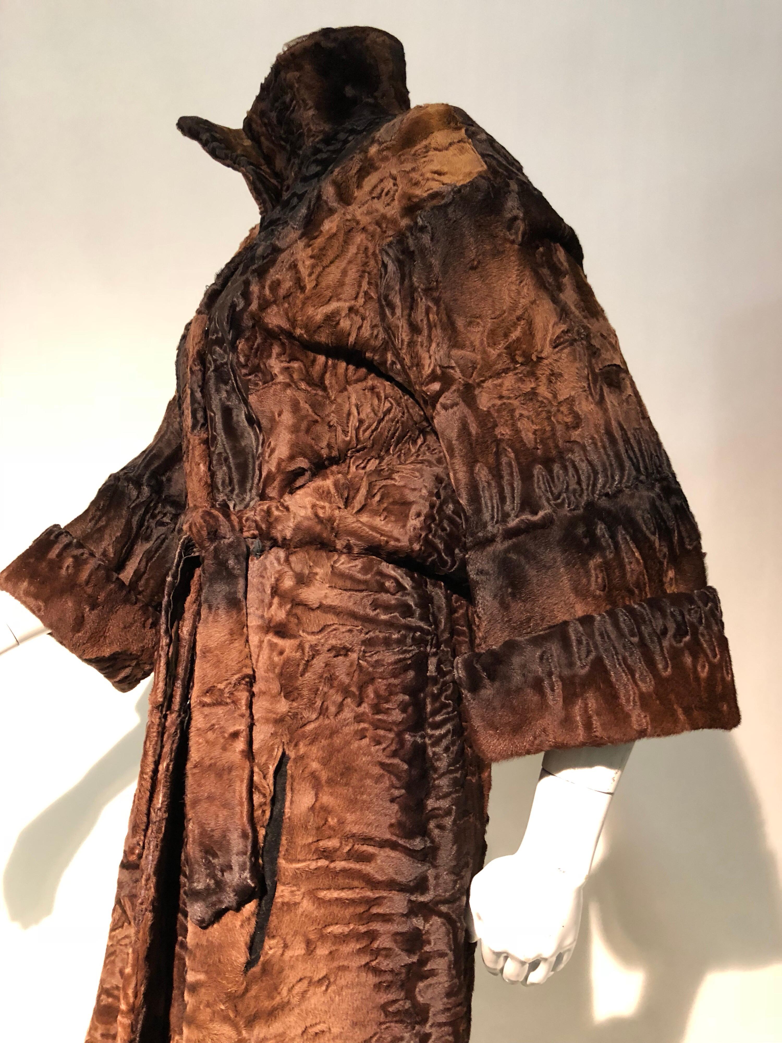 A delicious 1970s Windsor Royal chocolate and caramel brown swakara maxi coat with tall funnel neck. 3/4 length cuffed sleeves. Waist is gathered by a fur tie belt adding a definition to waistline. Lined in beautiful striped silk satin. Fitted at