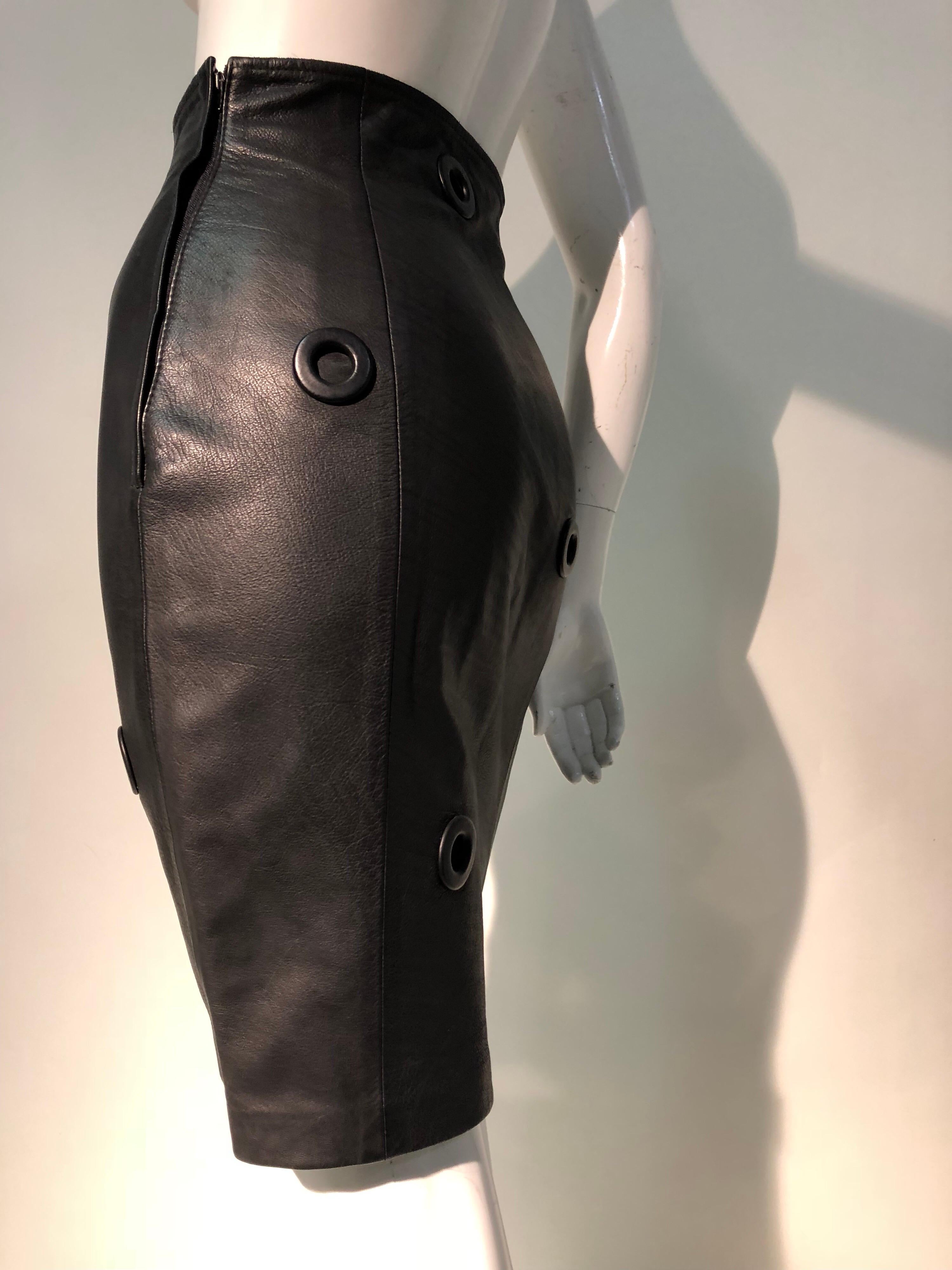 A 1980s Gianfranco Ferré high-waisted, soft and supple black leather sheath-cut mini skirt. Scattered around are large black metal eyelets set into the leather. Upper ones are backed lower are not. Satin acetate lined. Side zipper. 