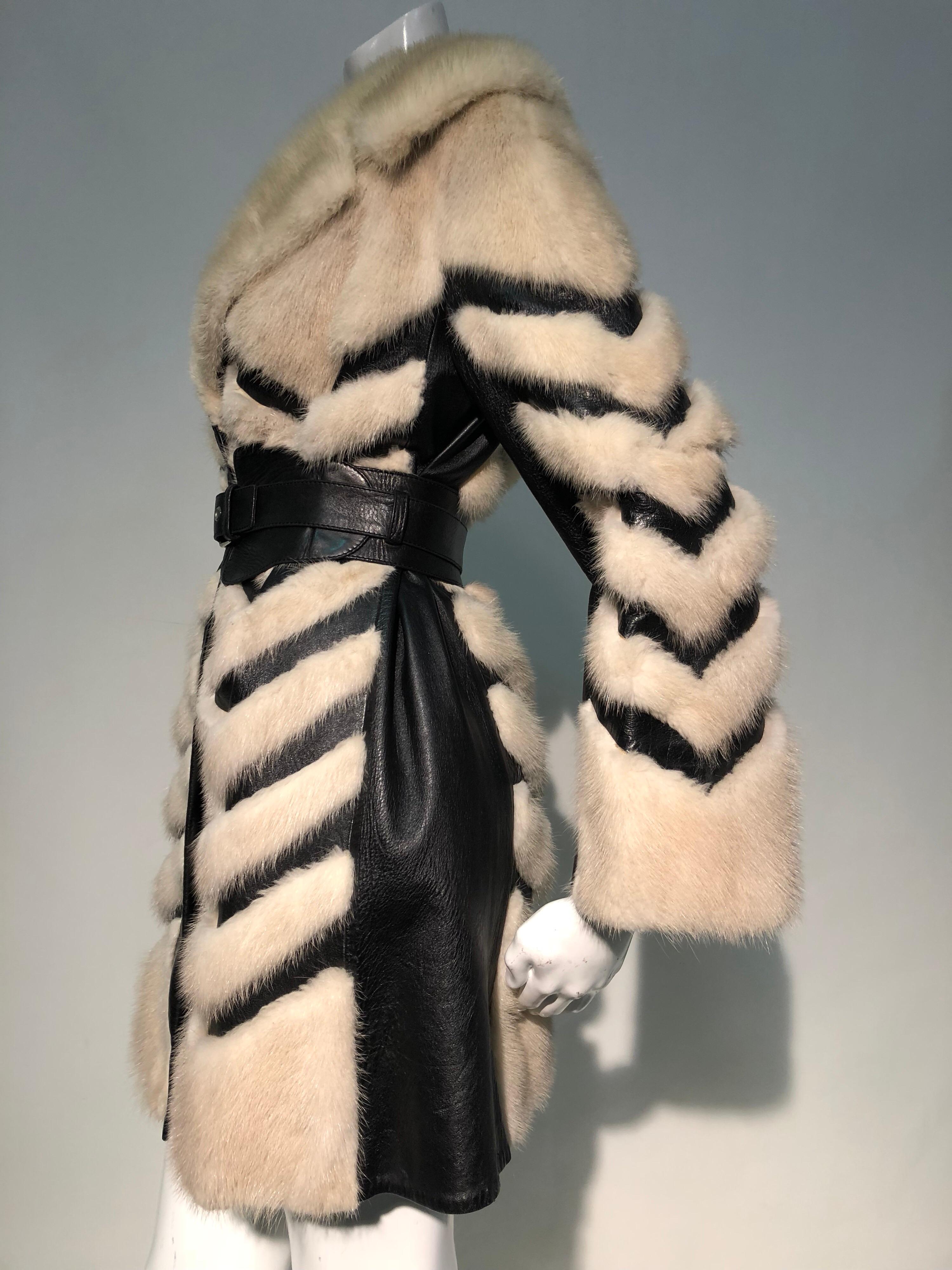 A striking 1960s honey blonde mink and black leather Mod styled coat with intricately pieced chevron design throughout. Large trench coat collar can be flipped up for extra warmth. Sold with a black leather corset-style belt (optional). Lining is a