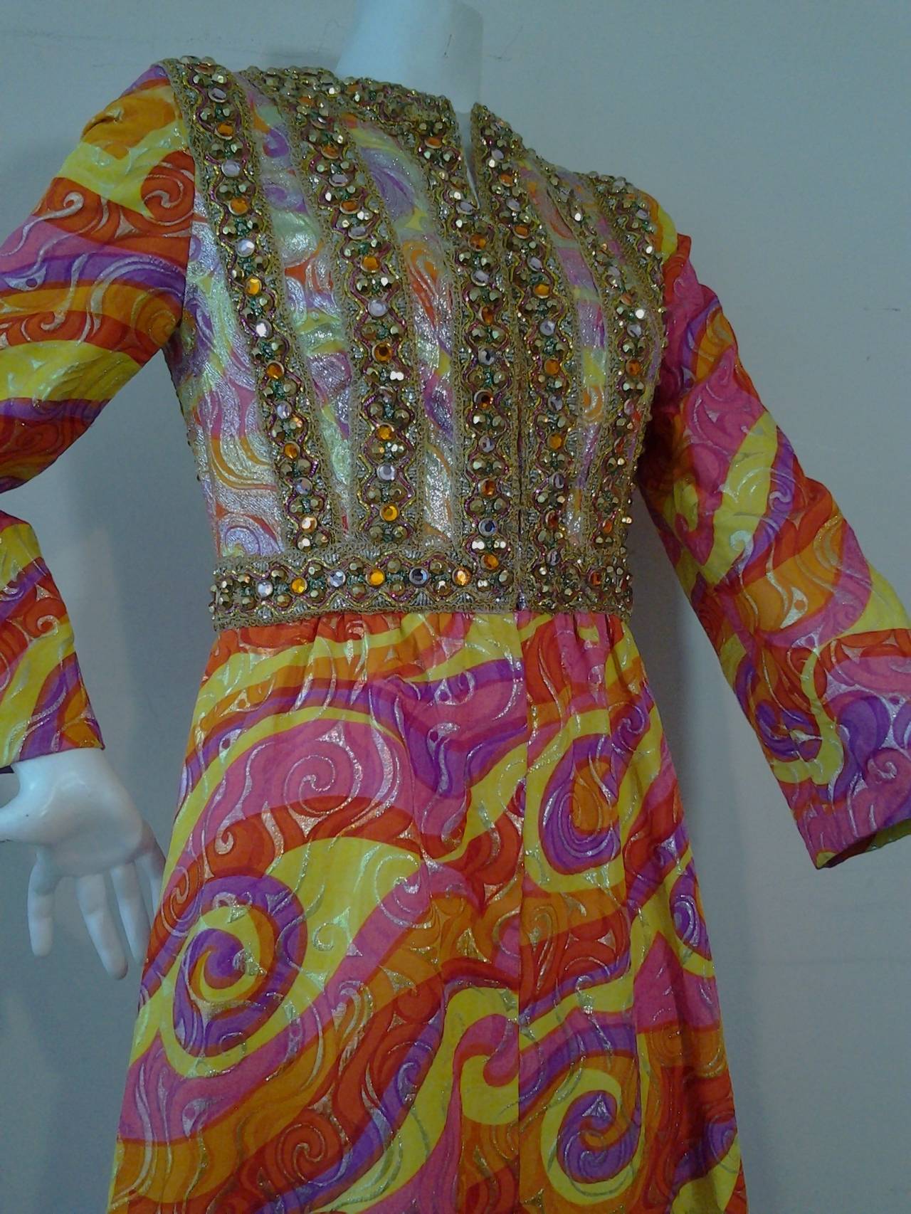 A fabulous 1960s Oscar de La Renta print lame brocade gown from I. Magnin.  Oscar label is gone.  Asian-inspired psychedelic wave print with heavily jeweled bodice.  Fully lined in yellow silk with 2 side slit pockets.  Snap and hook front closure.