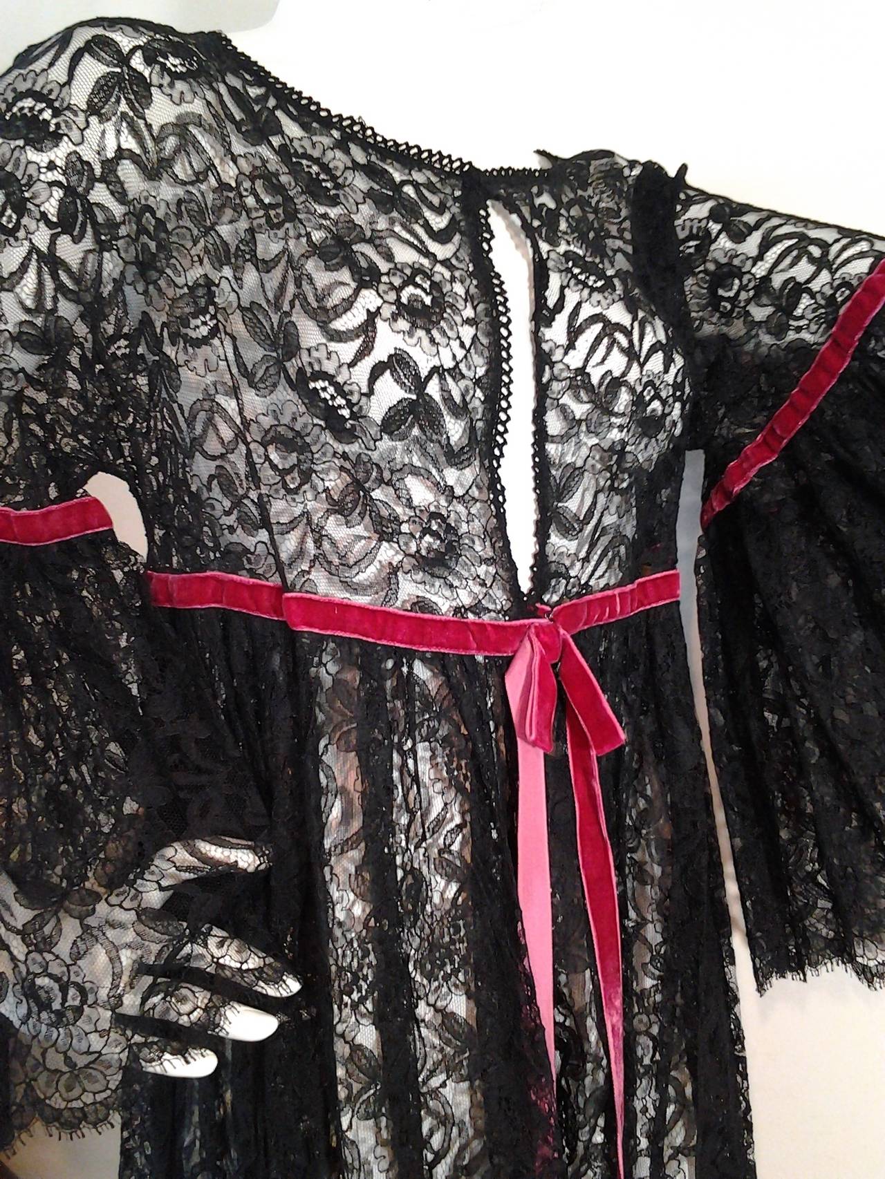 Beautiful 1960s Geno of California black lace baby doll robe with burgundy velvet trim at waist and sleeves.

Flared sleeve at elbow to wrist. Empire waist with front hook closure.