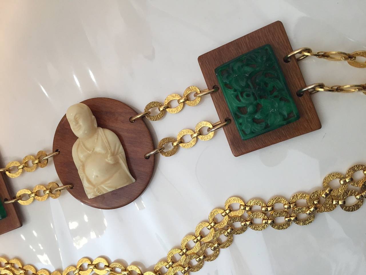 A fun 1960s chain belt with faux ivory and faux jade resin pieces mounted on wood.  Most likely made by Kenneth Jay Lane.  

Adjustible size.  37