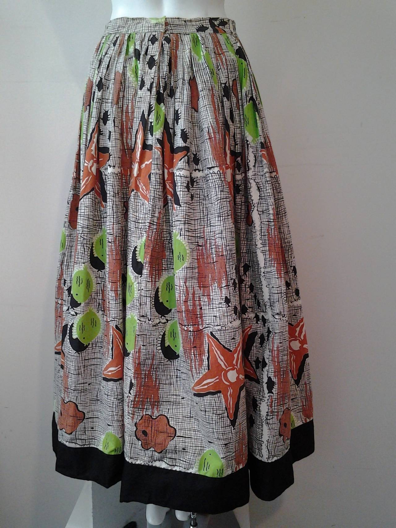 A wonderful 1940s brown, black and lime green seashell print pattered full skirt with decorative buttons at front, and wide black banded bottom.
