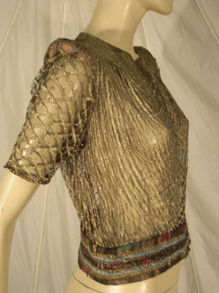 A stunning 1920s Art Deco French lame evening blouse:  lattice-work lame on silk tulle.  Beige silk shoulder pads.  Glass buttons down back of neck and snaps at left side.  Bottom hem is made from bands of lame and embroidered silk ribbon. 