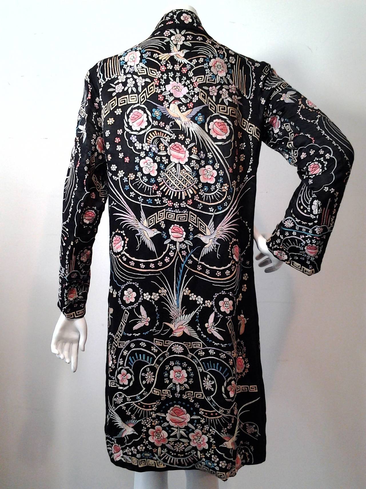 A spectacular silk satin 1920s duster jacket:  Lined in black silk charmeuse. Asymmetrical side button closure. Bird of paradise, butterfly and floral motifs throughout. Gorgeous.