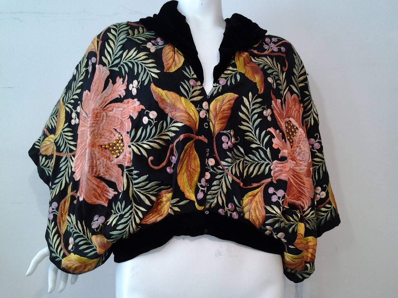 A 1930s blouson top: Made in the 30s with spanish embroidered silk shawl material.  Tiny buttons up the front. Silk velvet collar and waist band. Wide arm holes at side to waist giving a Dolman effect.