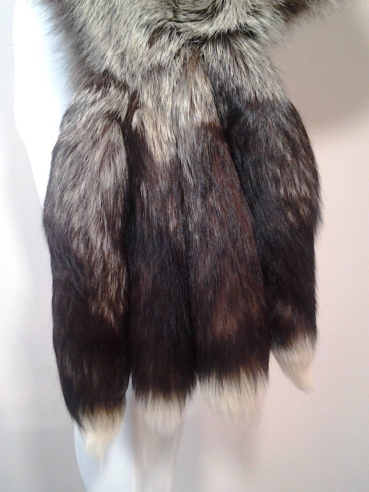 A huge, extravagant 1970s Revillon silver fox muff:  Silk lining with large zippered purse inside.  Silk ribbon handle attached inside.  At one end are 4 large, lush fox tails forming a fringe.