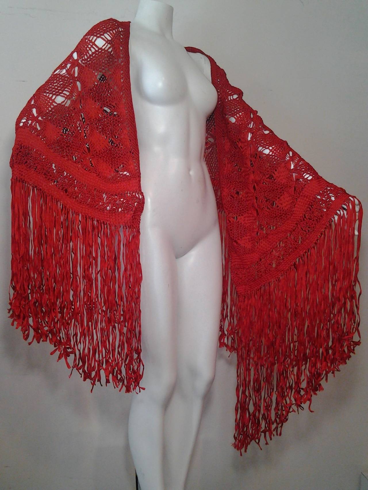 A gorgeous vibrant red ribbon macrame shawl from the 1970s with long fringed border.