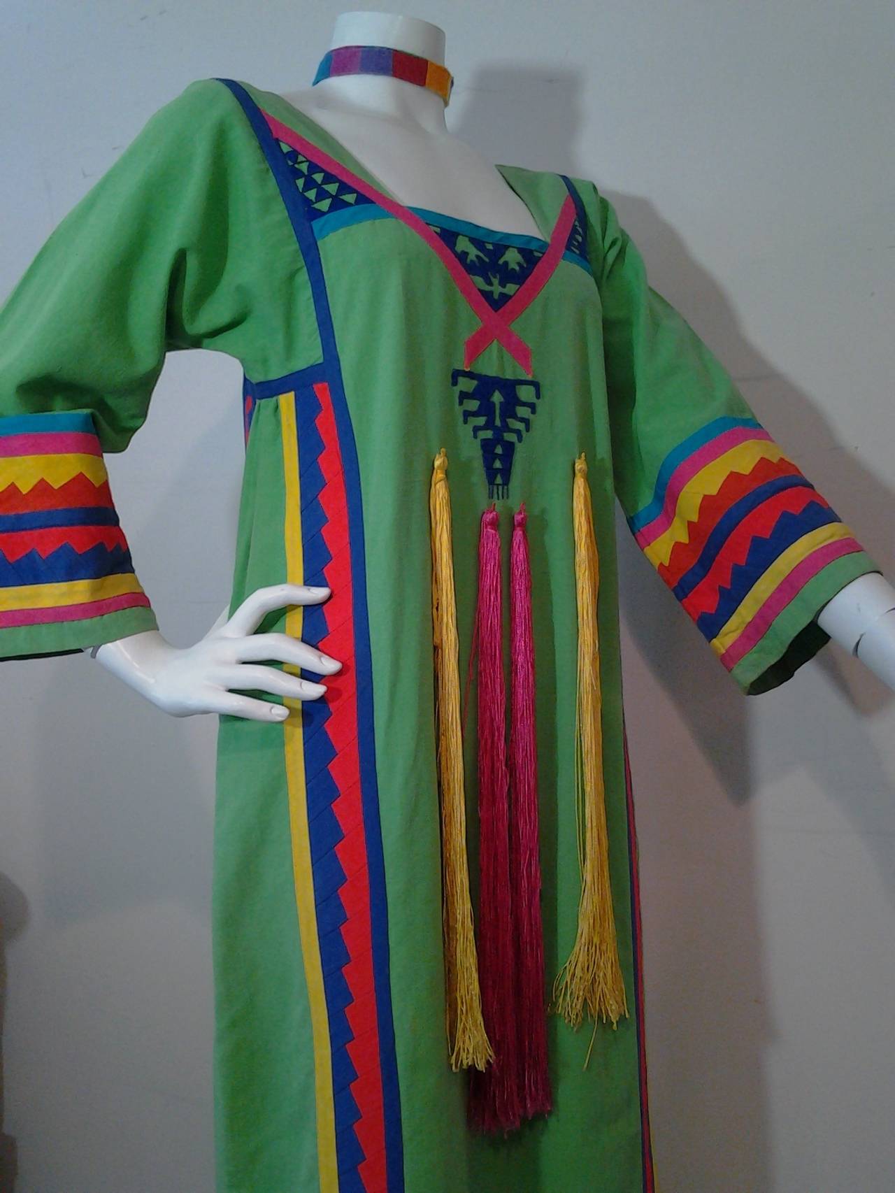 A 1970s Josefa Mexican cotton caftan: Empire styling with long tassel streamers down front and colorful applique at sleeves and throughout garment.