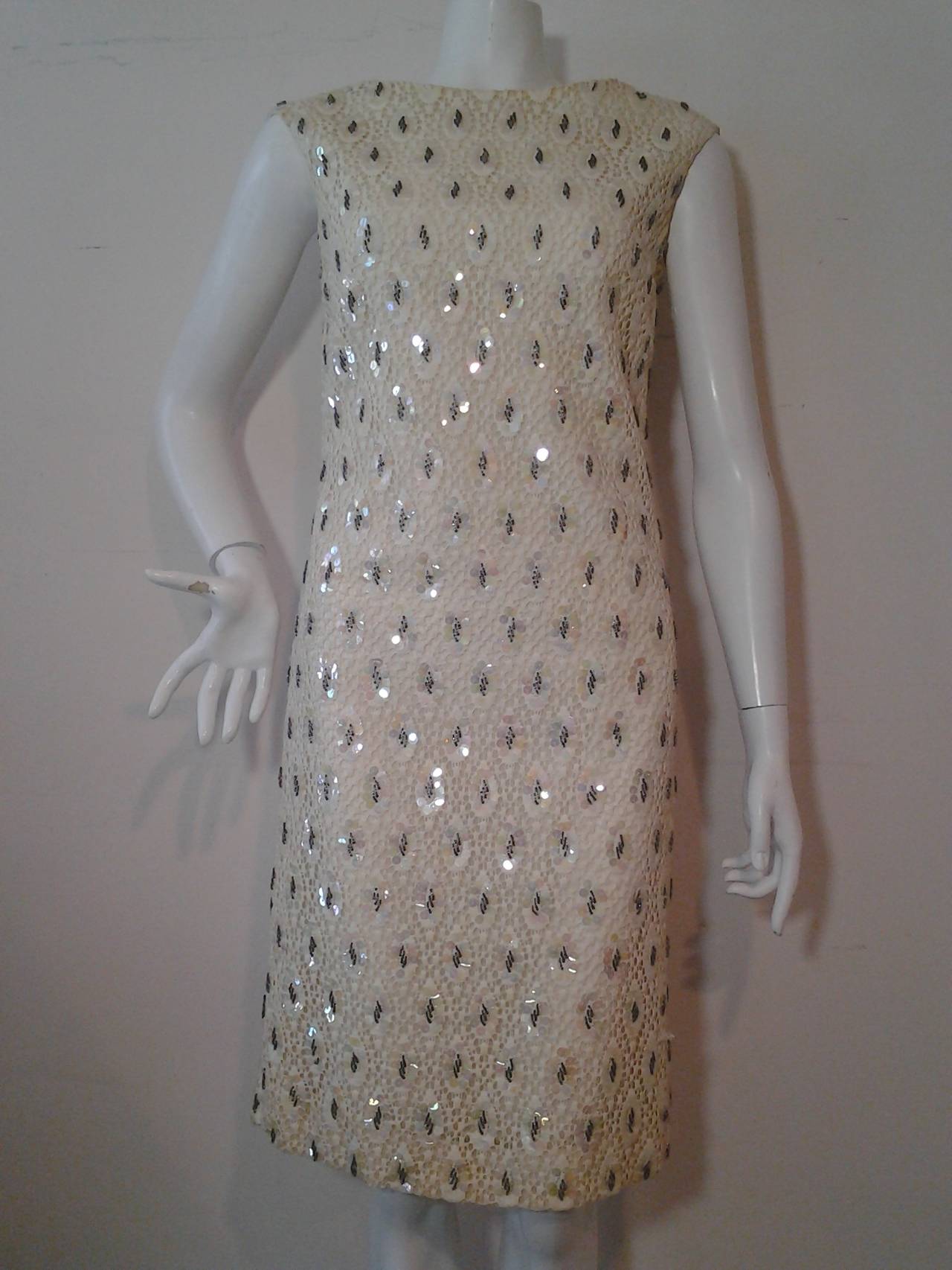 A gorgeous 1960s cotton lace sheath:  lace is backed with organza.  Additionally lined with white acetate.  Entire surface area is embellished with iridescent sequins and beaded drops. Boat neck. Zip back.