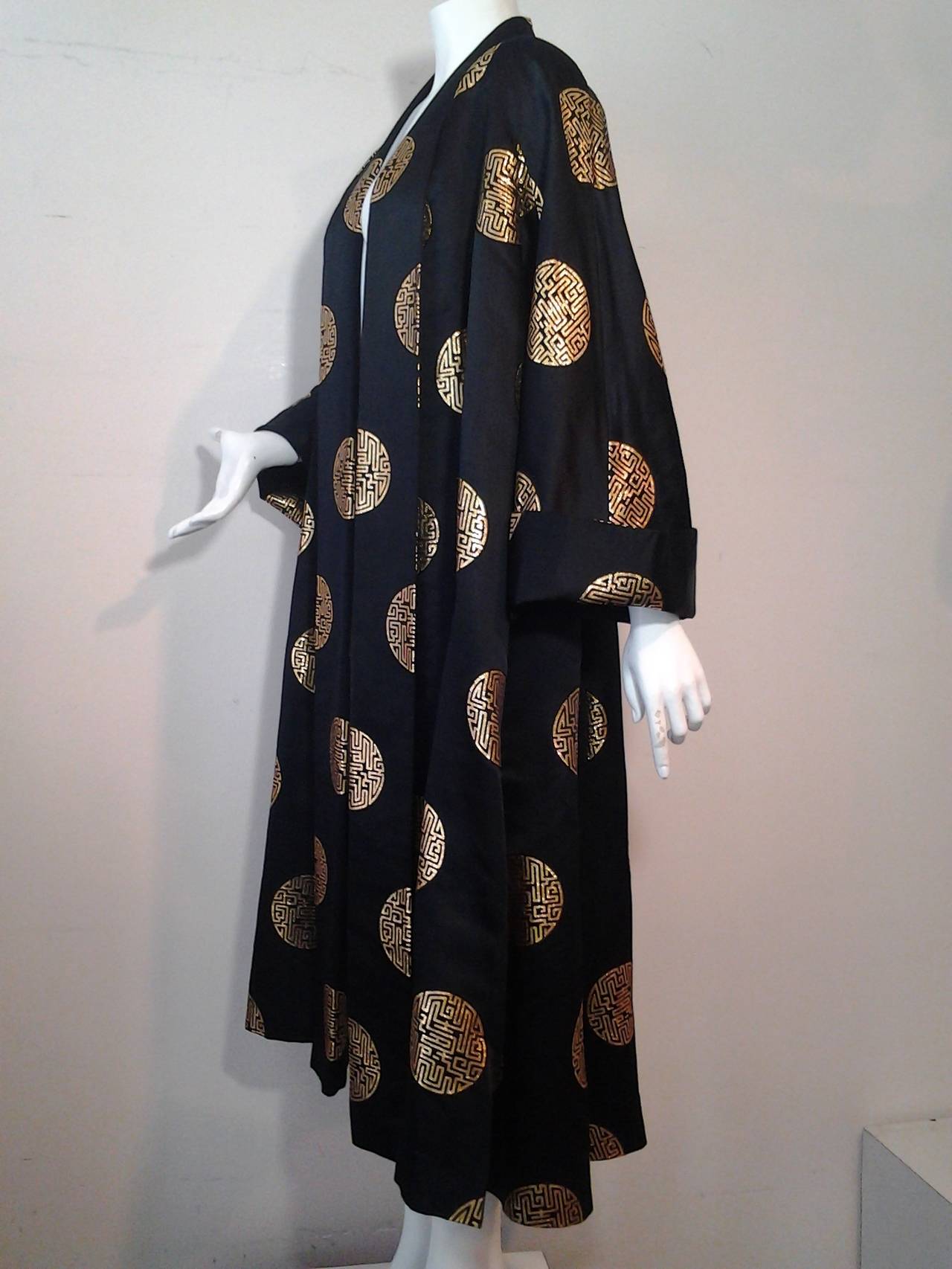 A gorgeous and dramatic 1950s Hong Kong silk satin opera coat cut in a full swing style, with large gold brocade medallions over entire coat. Lined in silk with deep cuffs.
