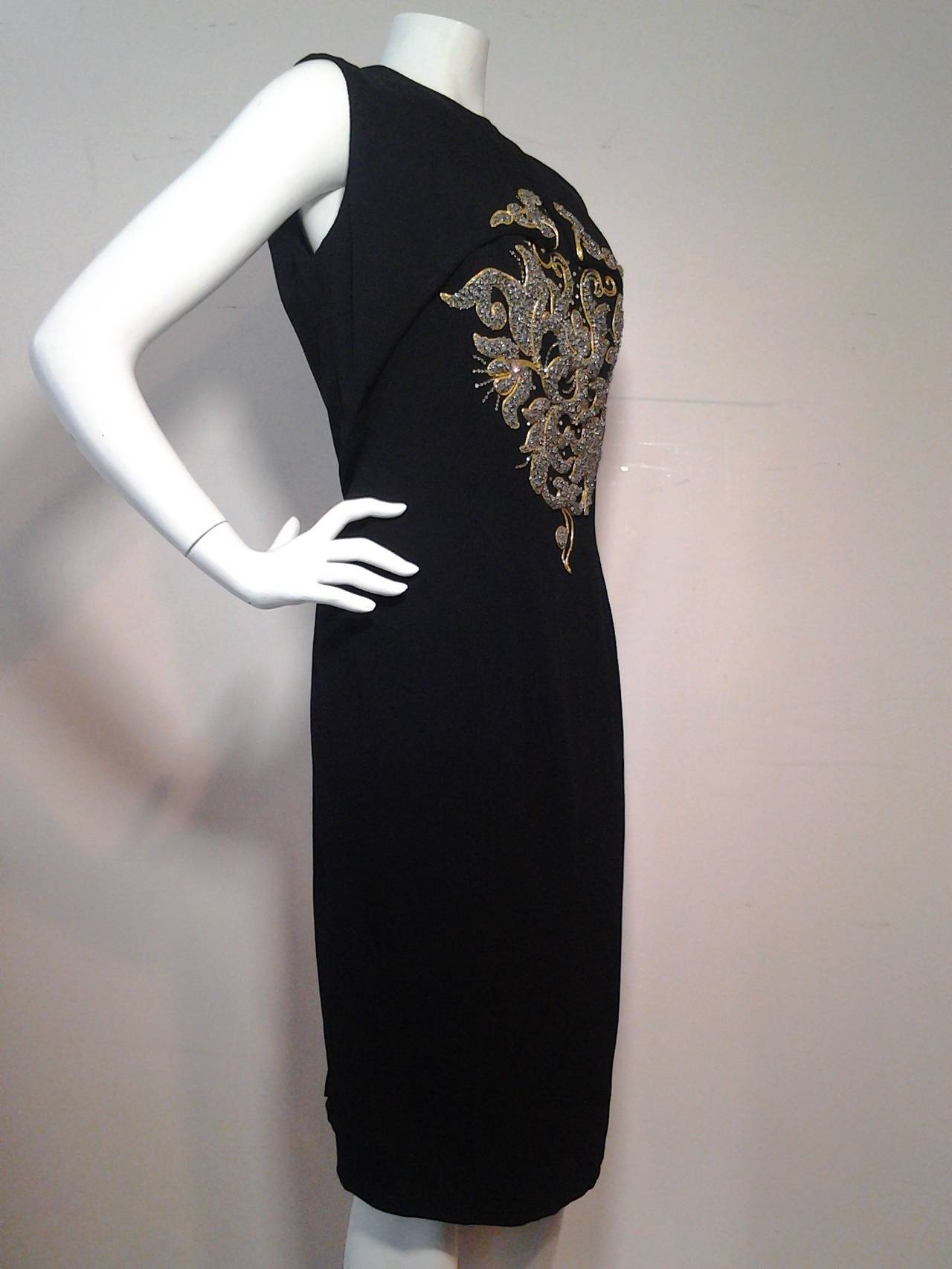A fantastic 1950s Mr. Blackwell 2-piece cocktail dress and vest.  Black silk crepe spaghetti strap sheath with an incredible and finely wrought beaded and embroidered crest in metallics: gold and silver.  To top it off is a small bolero vest with