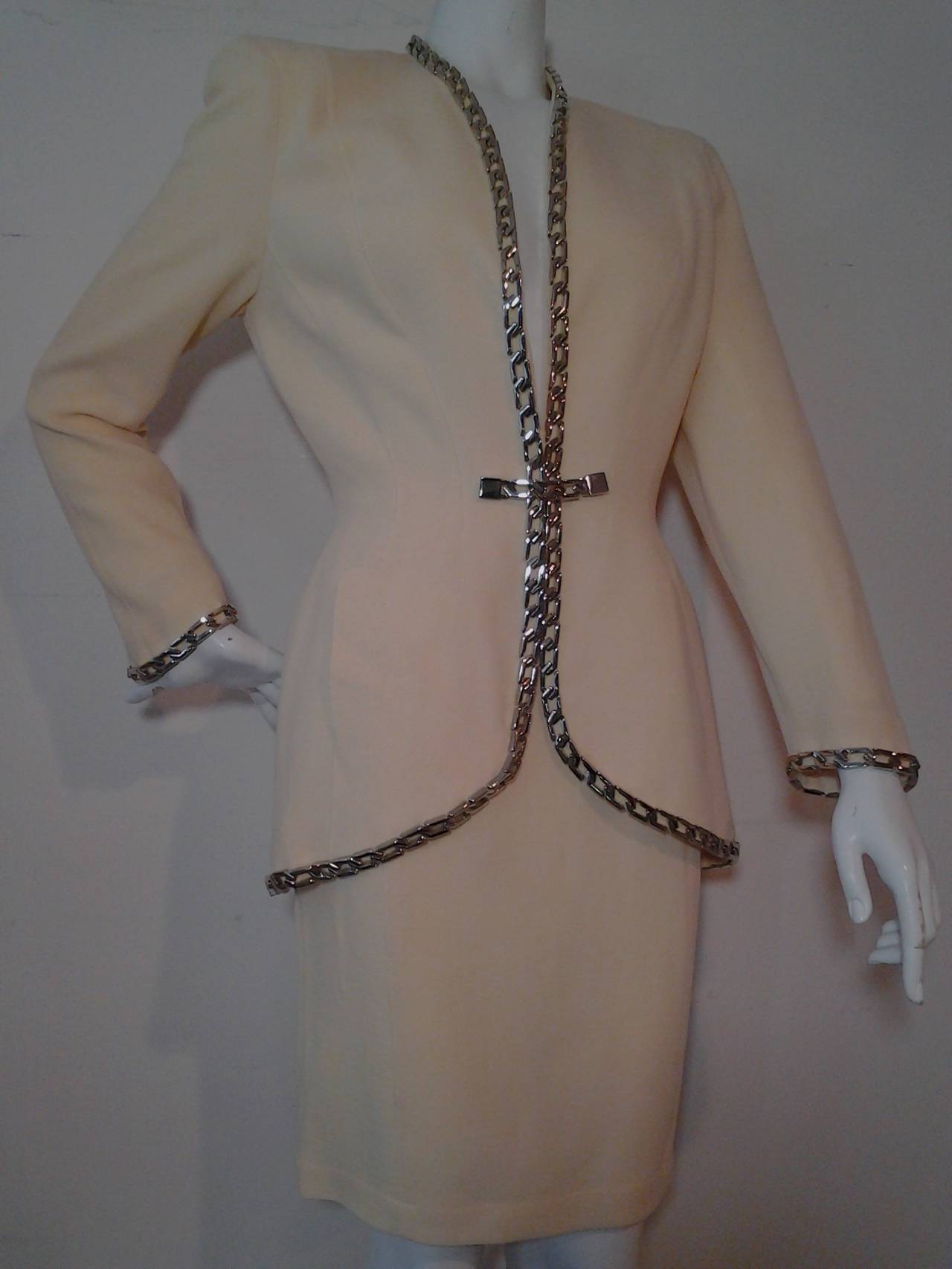 A chic 1980s Thierry Mugler skirt suit: wool novelty crepe sculpted in signature Mugler style and trimmed with silver chain link trim.  Fully lined. Size 38.