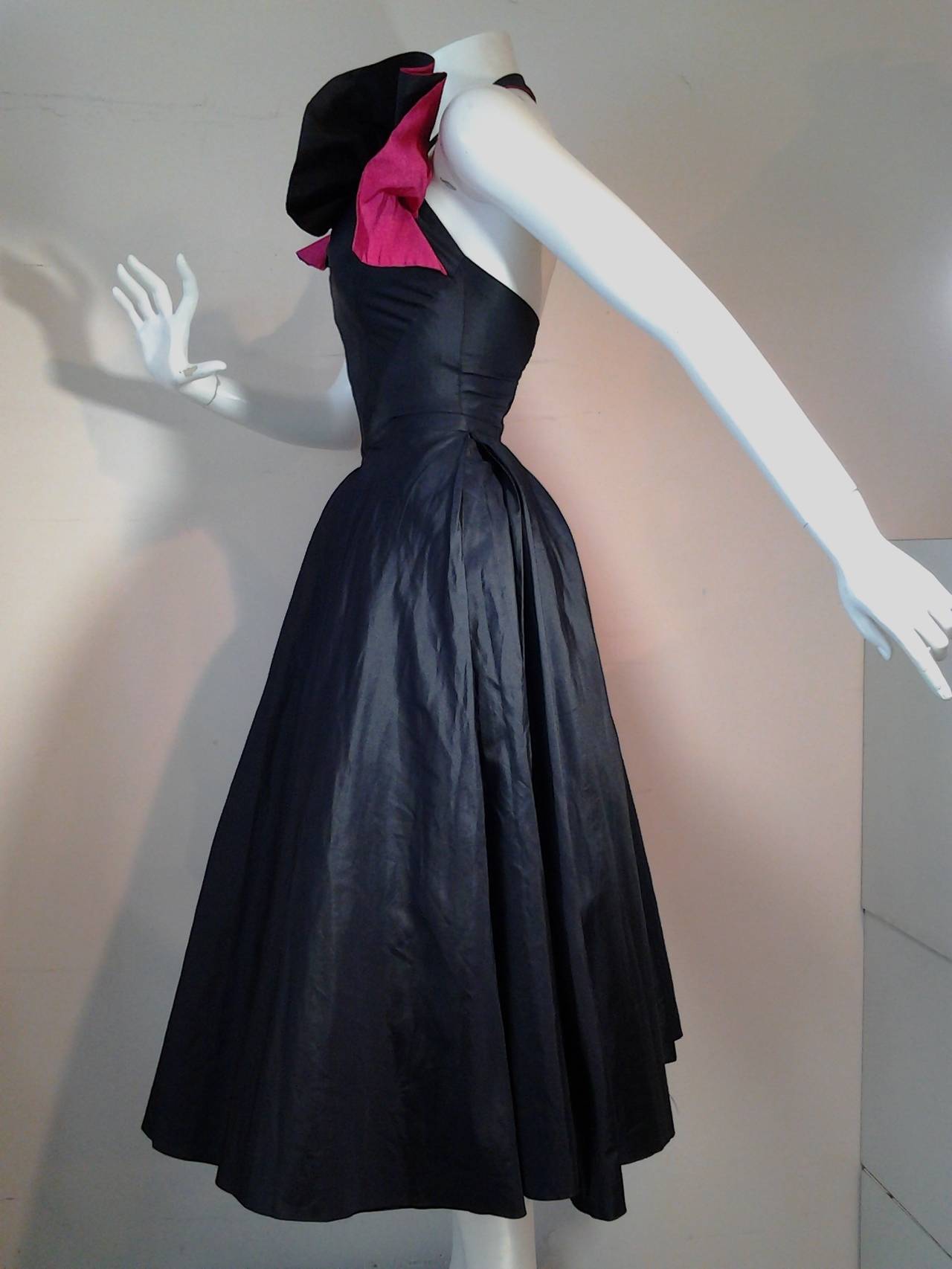A gorgeous early 1950s midnight blue silk taffeta halter dancing dress:  full skirt with heavy inverted pleats at center front. Corset-style fit seaming in bodice. Fuchsia silk faille ruffled décolletage. Wide horsehair braid inside dress hem. 