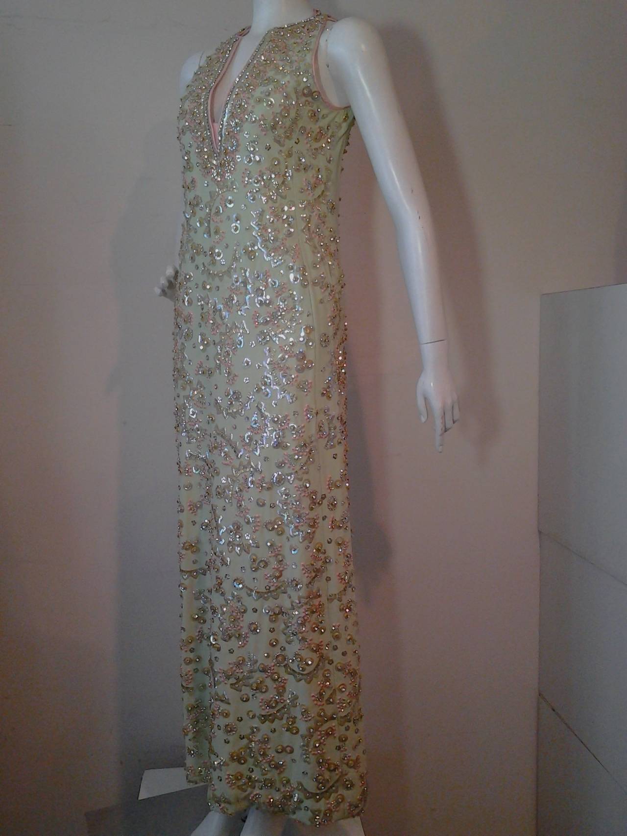 A stunning 1960s sleeveless gown:  Beautiful mint green silk gown, lined with a deep V-cut neckline edged in coral silk.  All-over sequins and beading in a Indian-inspired style--heavier around neckline and lighter all-over. Back zipper.