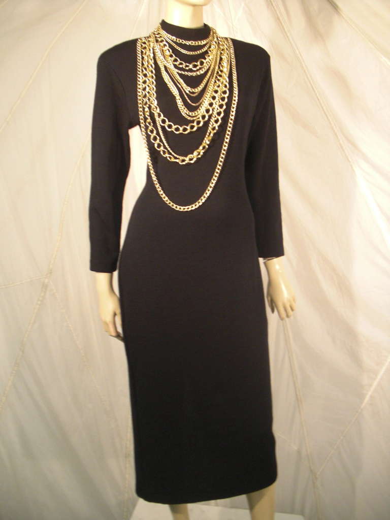 A 1990s Andrea Jovine super sexy knit dress with open back and high slit.  Front neckline features lavish gold chainlink necklaces attached to the dress.