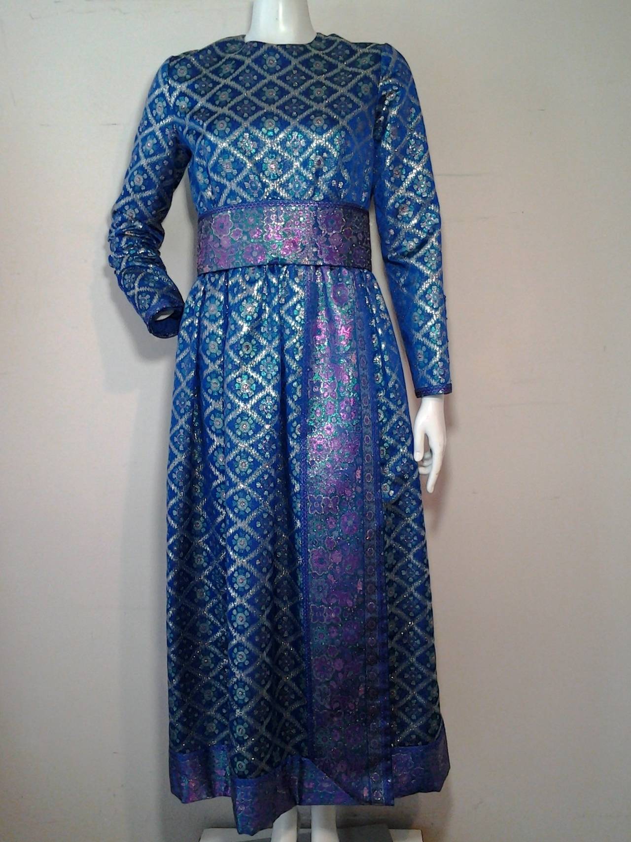 A beautiful 1960s Oscar de la Renta aqua, fuchsia and silver brocade gown with long sleeves and an obi-inspired waist band and long sash detail. Completely lined.  Originally sold at Montalvo's.