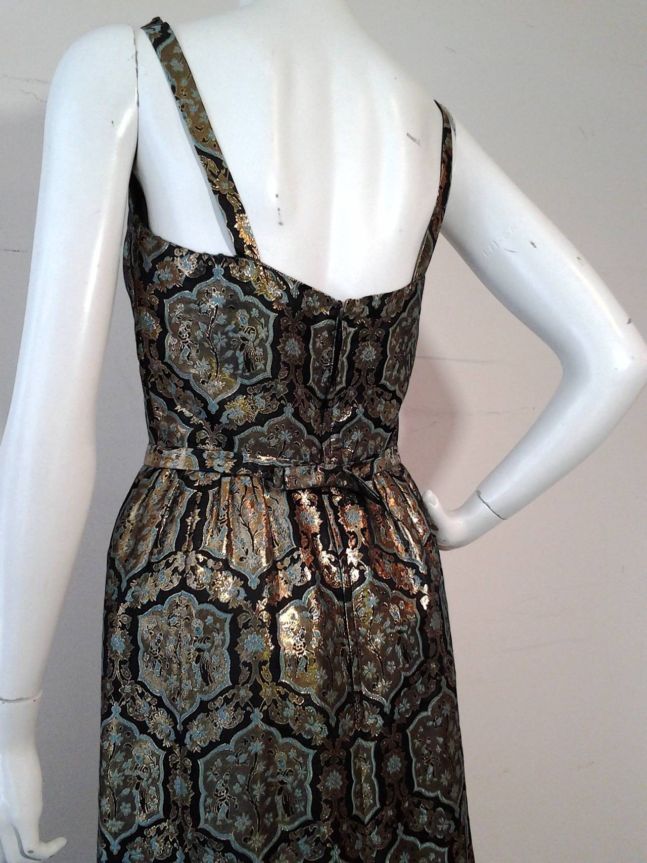 A gorgeous 1960s full-length lame brocade sheath dress in a Moorish-inspired pattern.  slightly gathered shirt. Low cut back. Back zipper.
