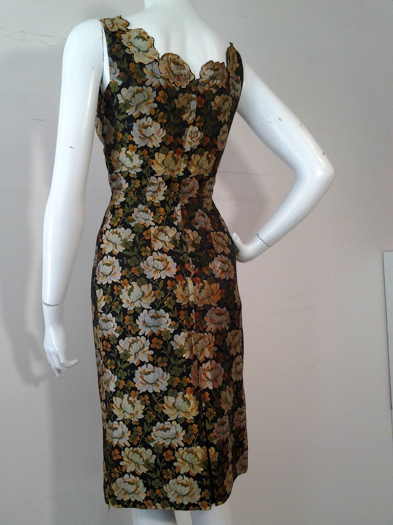 A gorgeous 1950s floral brocade sheath in brown gold and black.  Neckline is hand appliqued with flowers cut from the fabric.  An overskirt that hooks at waist is included, though there are a few stains on it. (They could be removed by making some